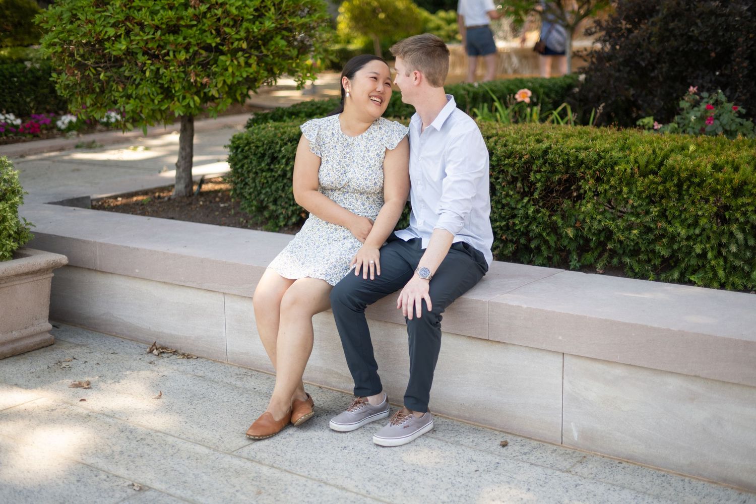 A couple shares tender moments during an outdoor photoshoot on stone steps surrounded by greenery.