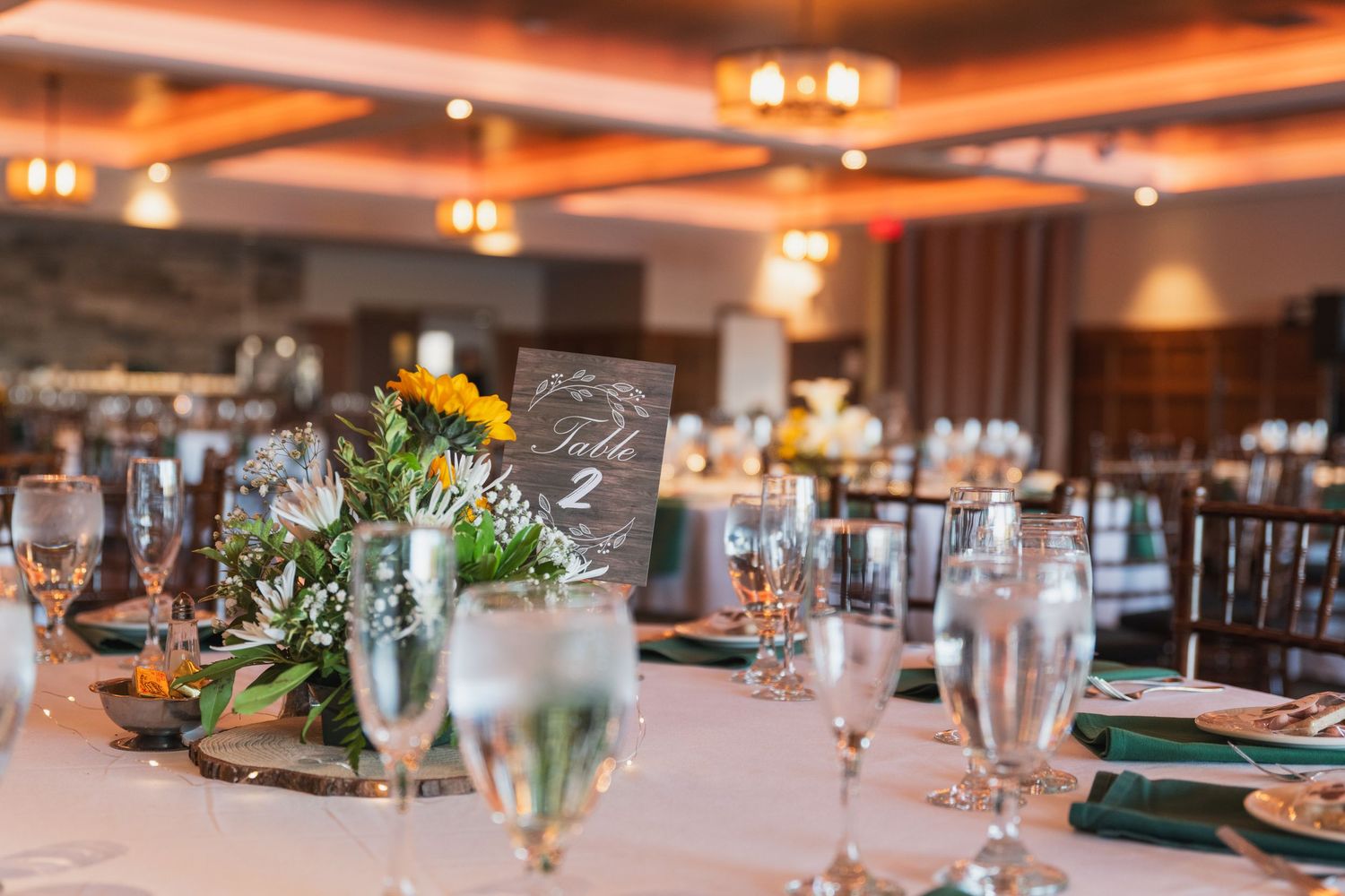 Elegant wedding reception table settings with floral centerpieces and glowing ambient lighting.