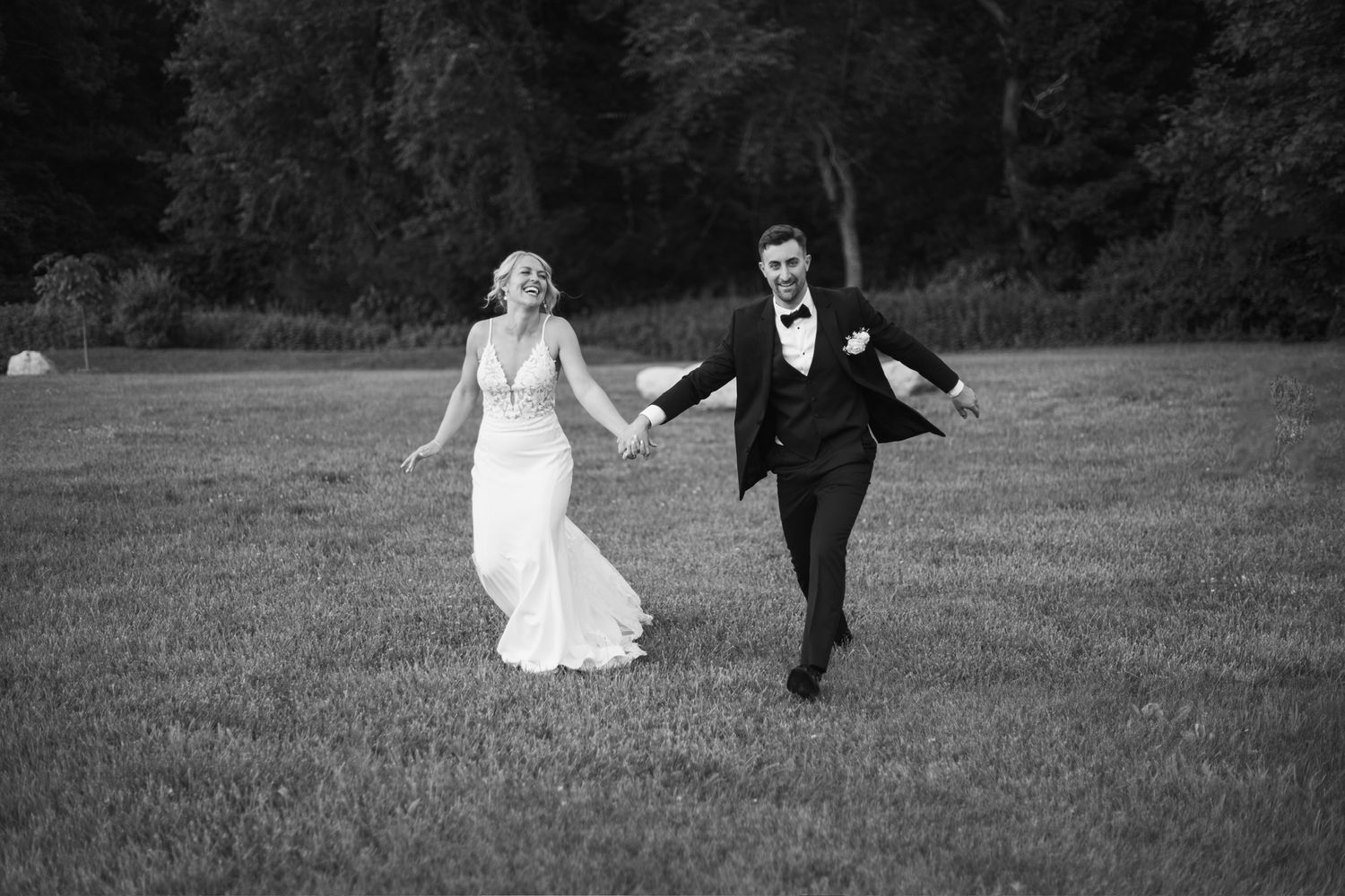 Black and white photos of joyful newlyweds running and dancing in an open field.