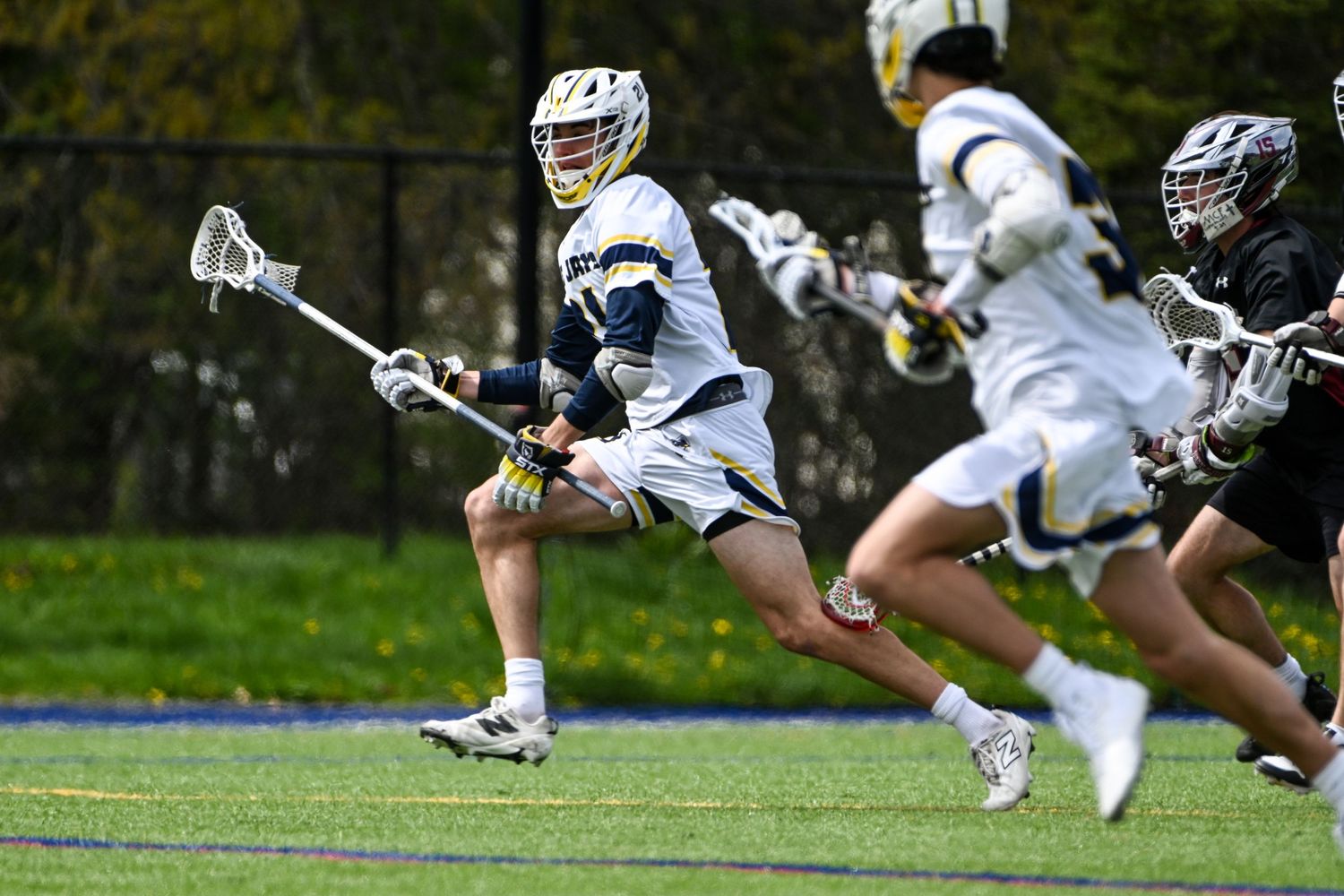 A Blue Jays lacrosse player sprints with the ball during an outdoor collegiate lacrosse match.