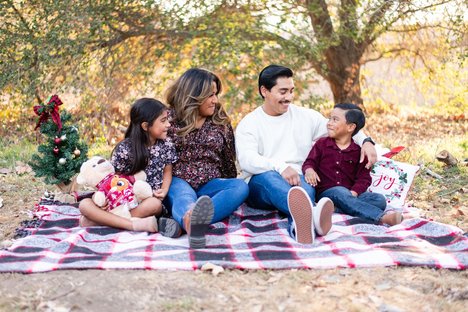 Family relaxing on picnic blankets during golden hour in an autumn setting.