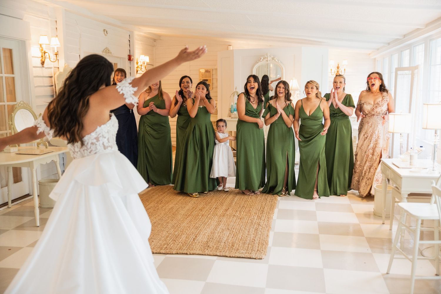 Wedding party gathering in an elegant white room with bridesmaids in sage green dresses.