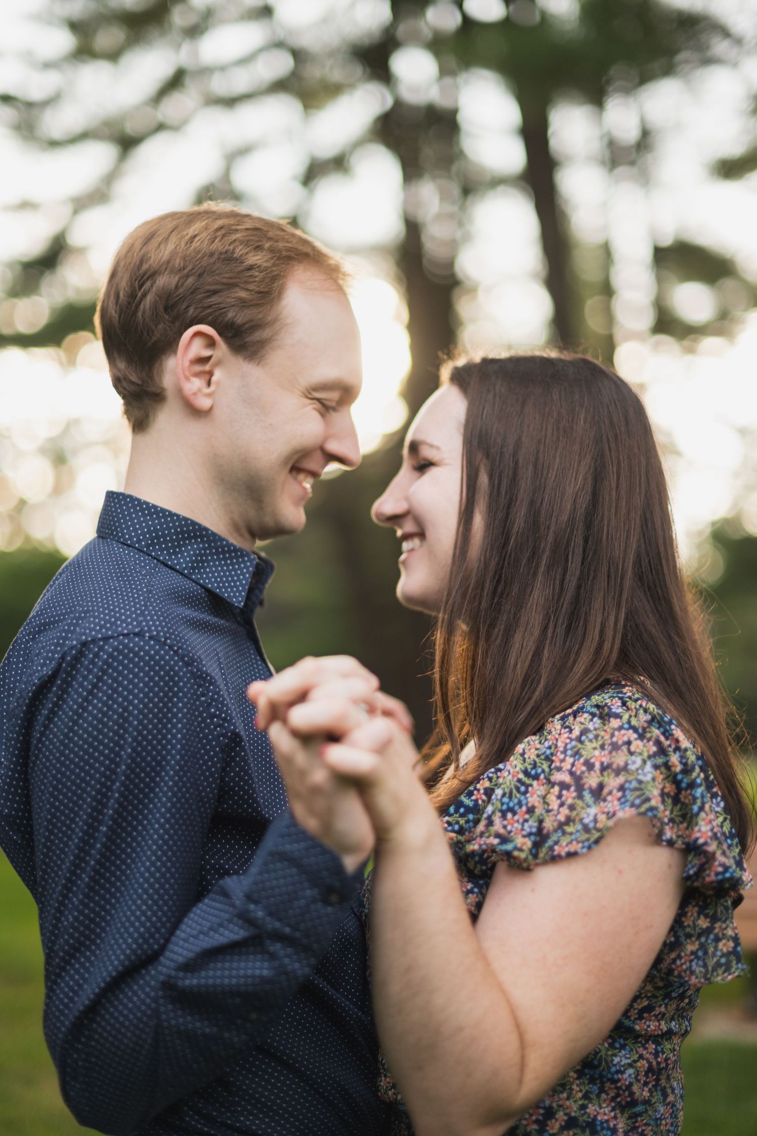 Romantic engagement photos of couple in navy and floral outfits sharing intimate moments.
