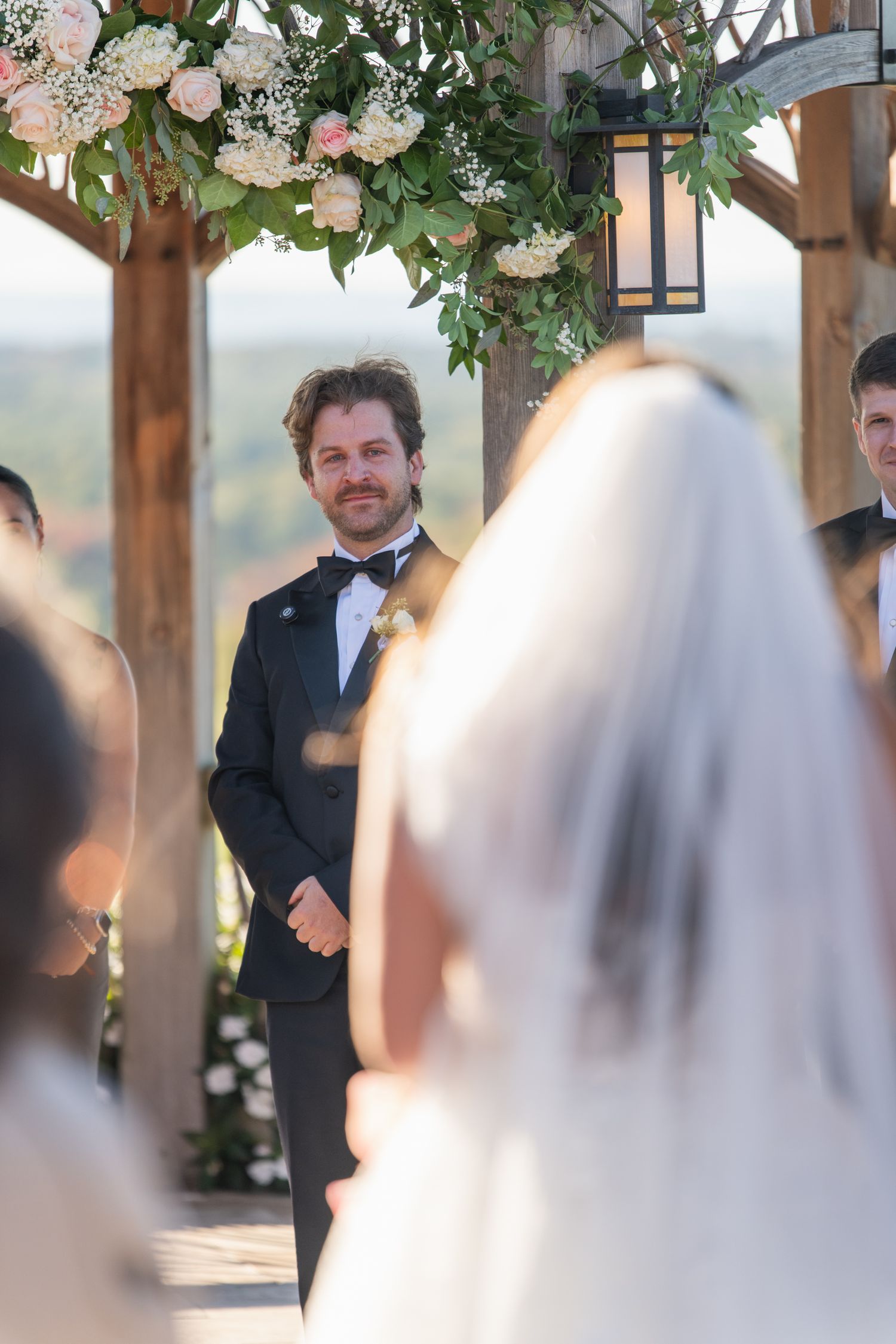 A series of wedding ceremony photos showing a couple during their first look moment under a floral-decorated pergola.