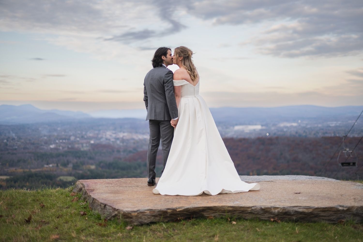 Scenic mountain overlook wedding portraits with dramatic cloudy sky and valley views.