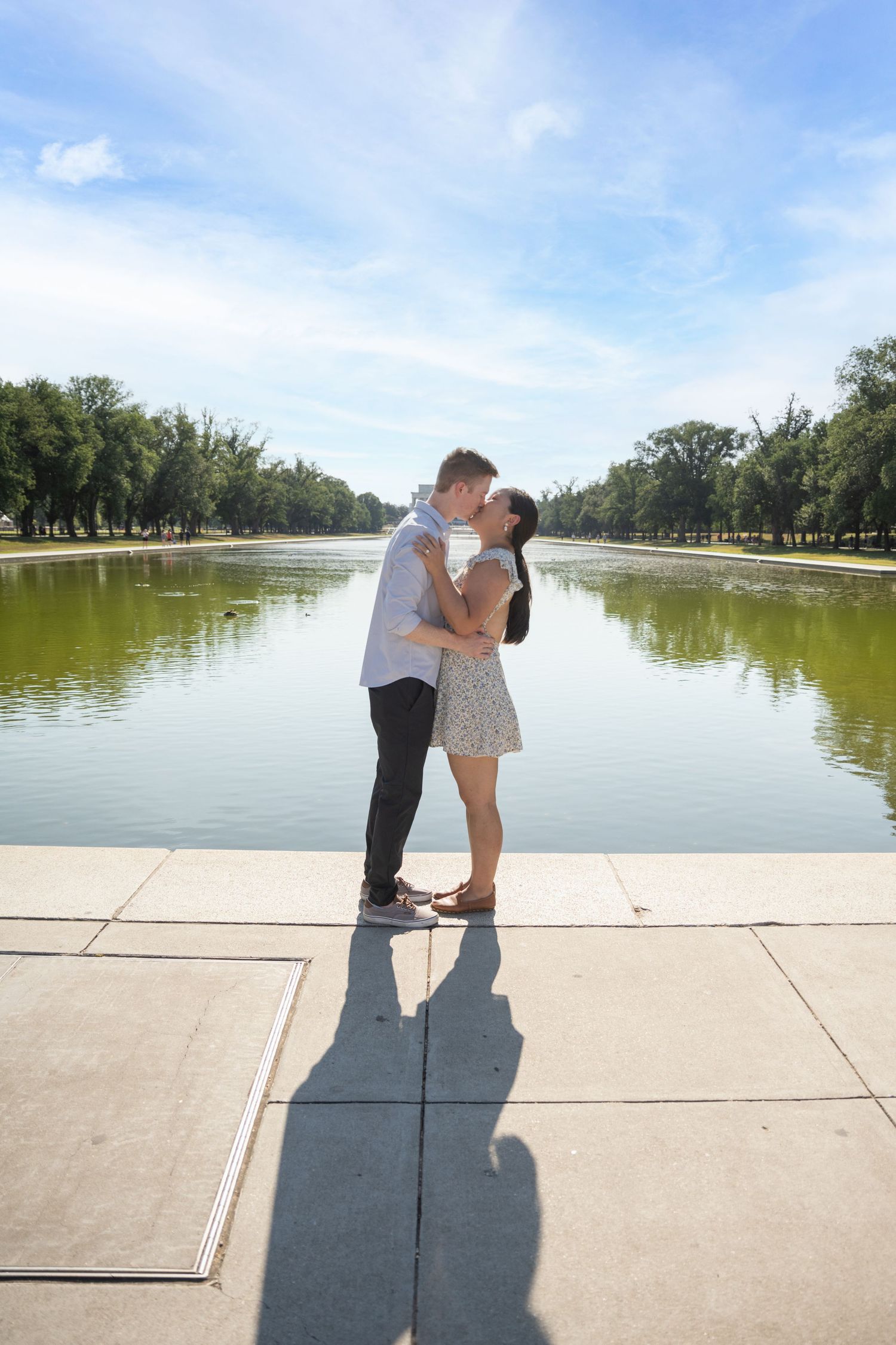 A lakeside proposal photo series showing silhouettes against a bright blue sky and calm waters.