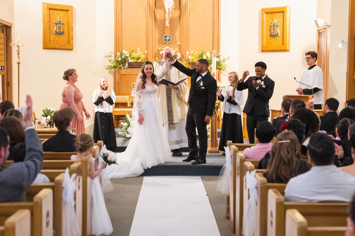 Wedding ceremony taking place in a traditional church sanctuary with wooden pews.