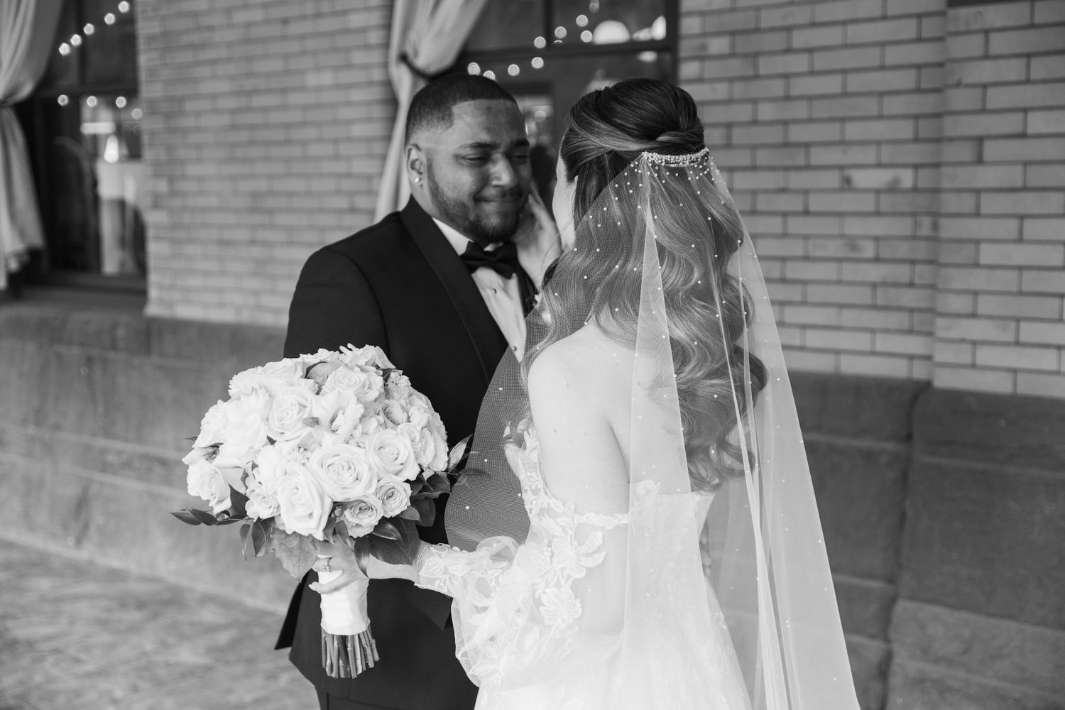 Elegant black and white wedding photos featuring formal attire and bouquets against a brick wall.