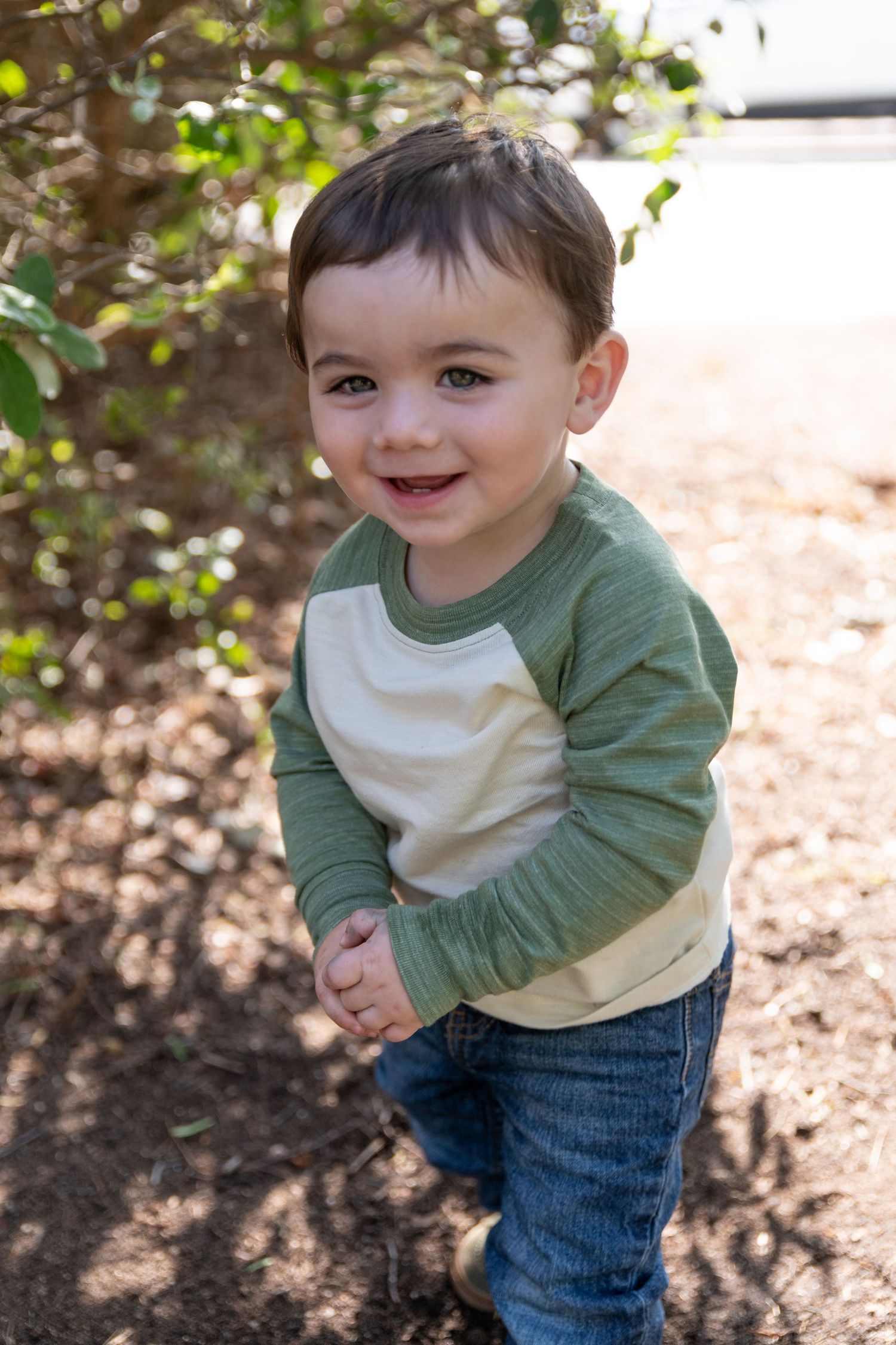 Energetic sequence of a toddler playing and laughing in a green raglan shirt and jeans.
