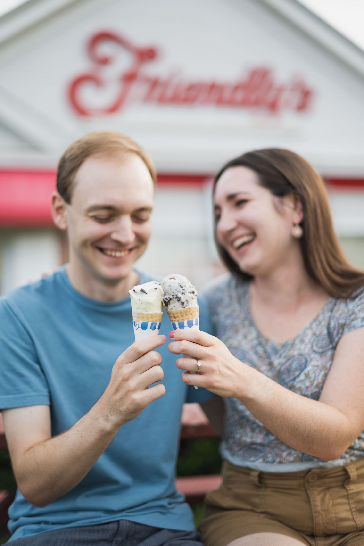 Couple shares ice cream cones outside Friendly's restaurant with joyful expressions.