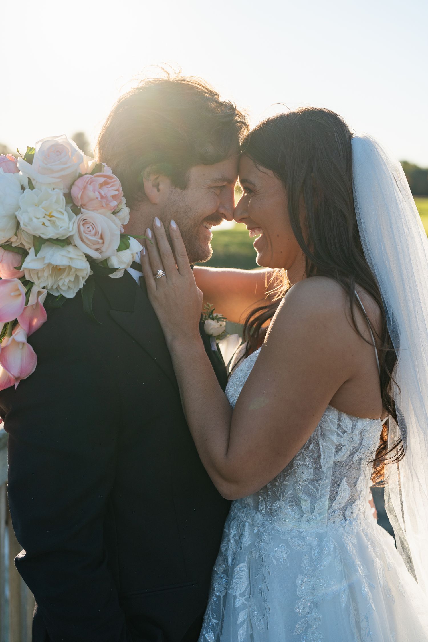 Romantic wedding couple sharing intimate moments at sunset with pink floral decorations.
