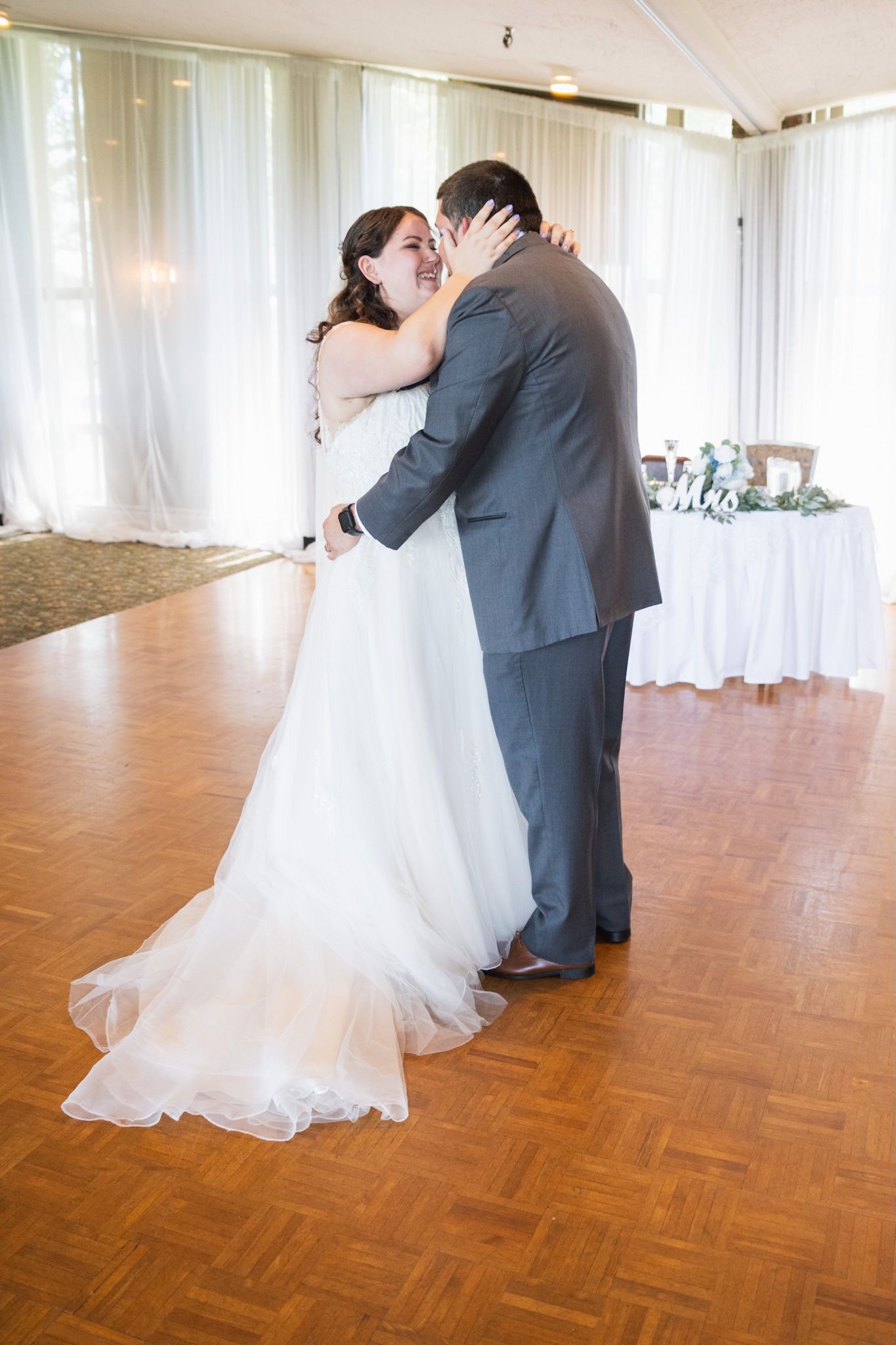 First dance moment captured in an elegant venue with parquet flooring.