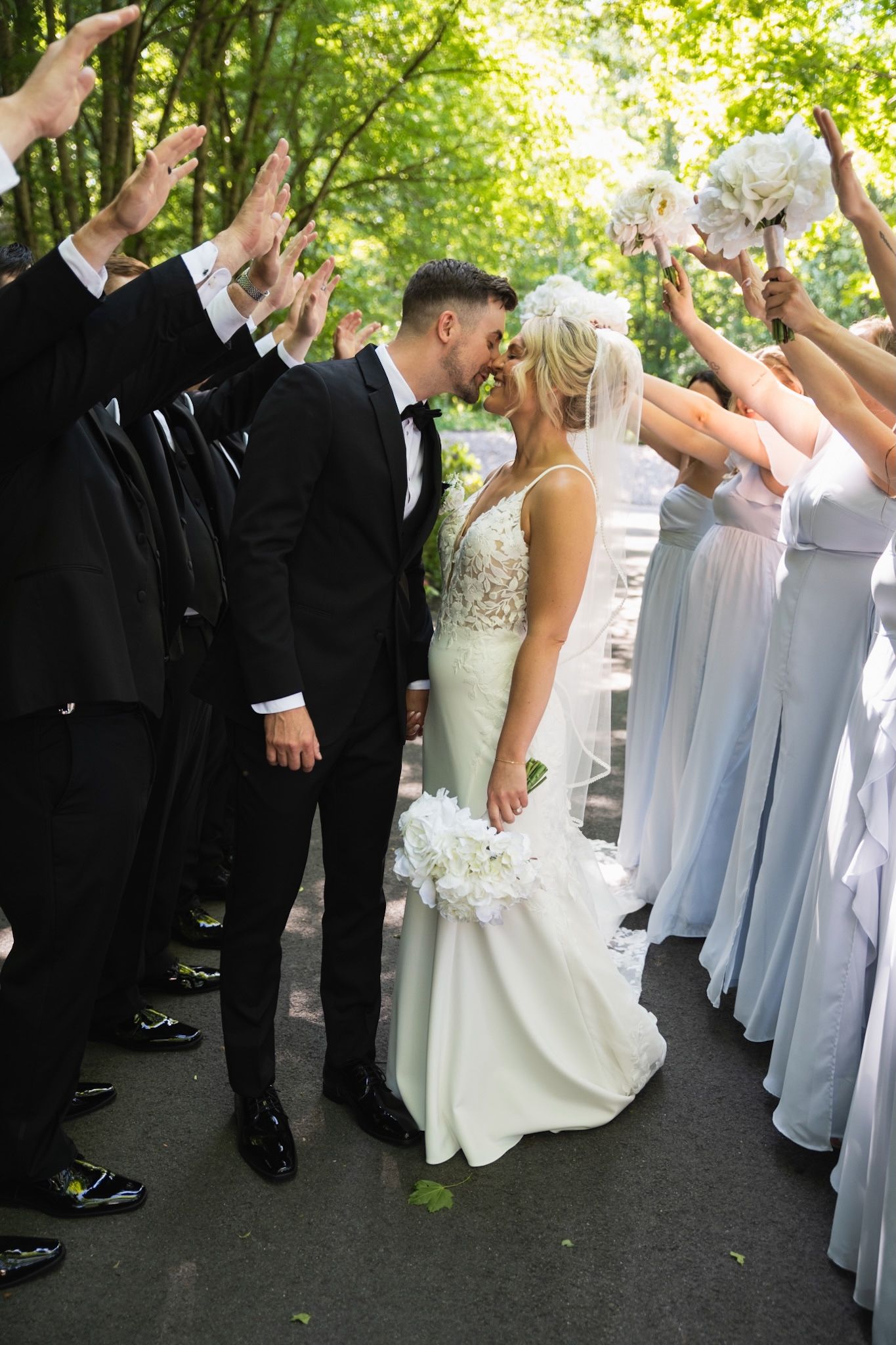 Wedding celebration with guests in formal attire dancing and cheering outdoors.