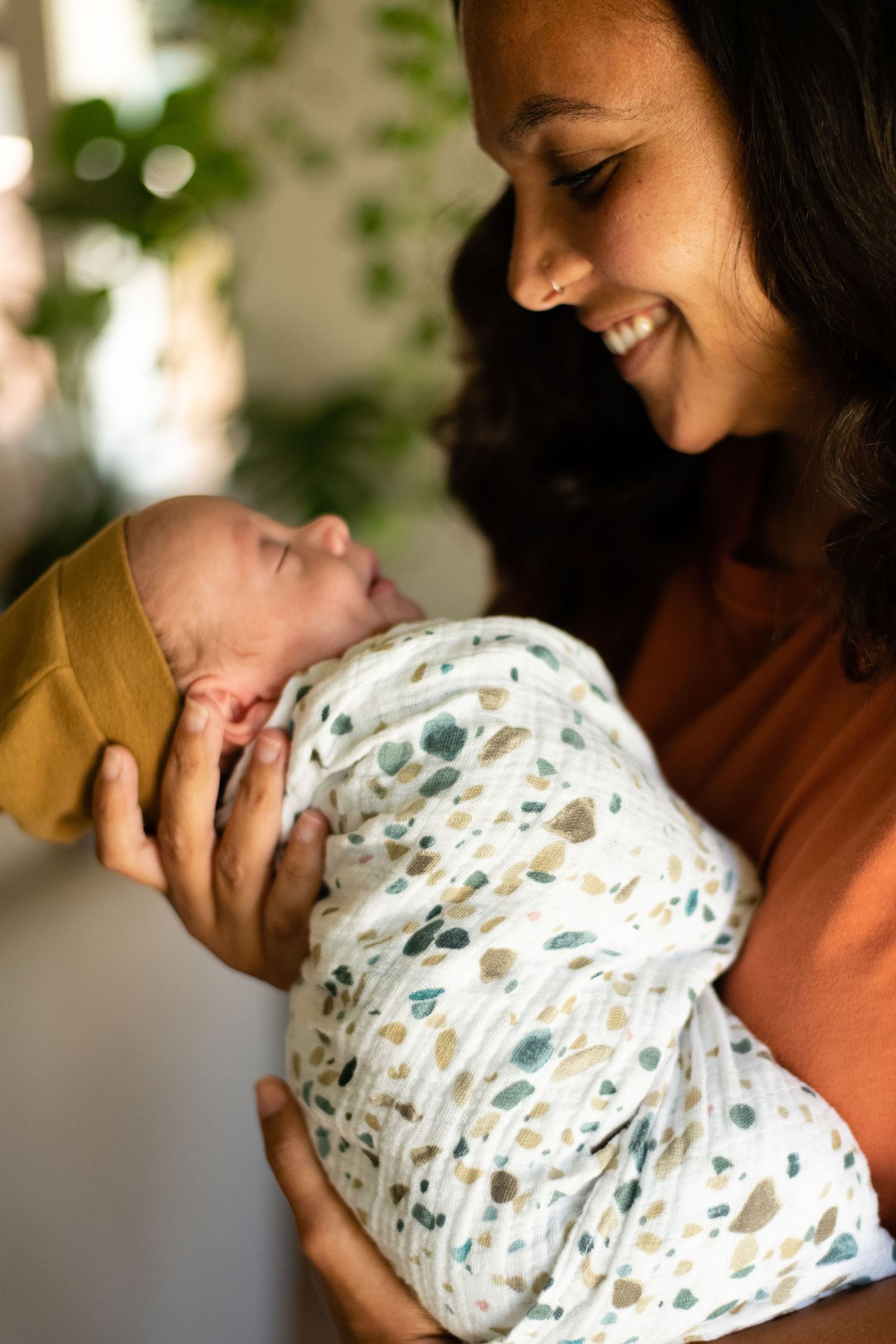 Tender moment captured of swaddled newborn being cradled and kissed in warm indoor lighting.