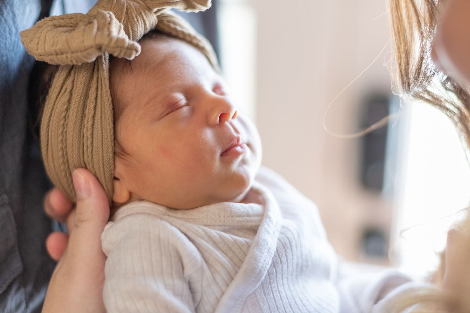 A sleeping newborn baby wrapped in soft white fabric.