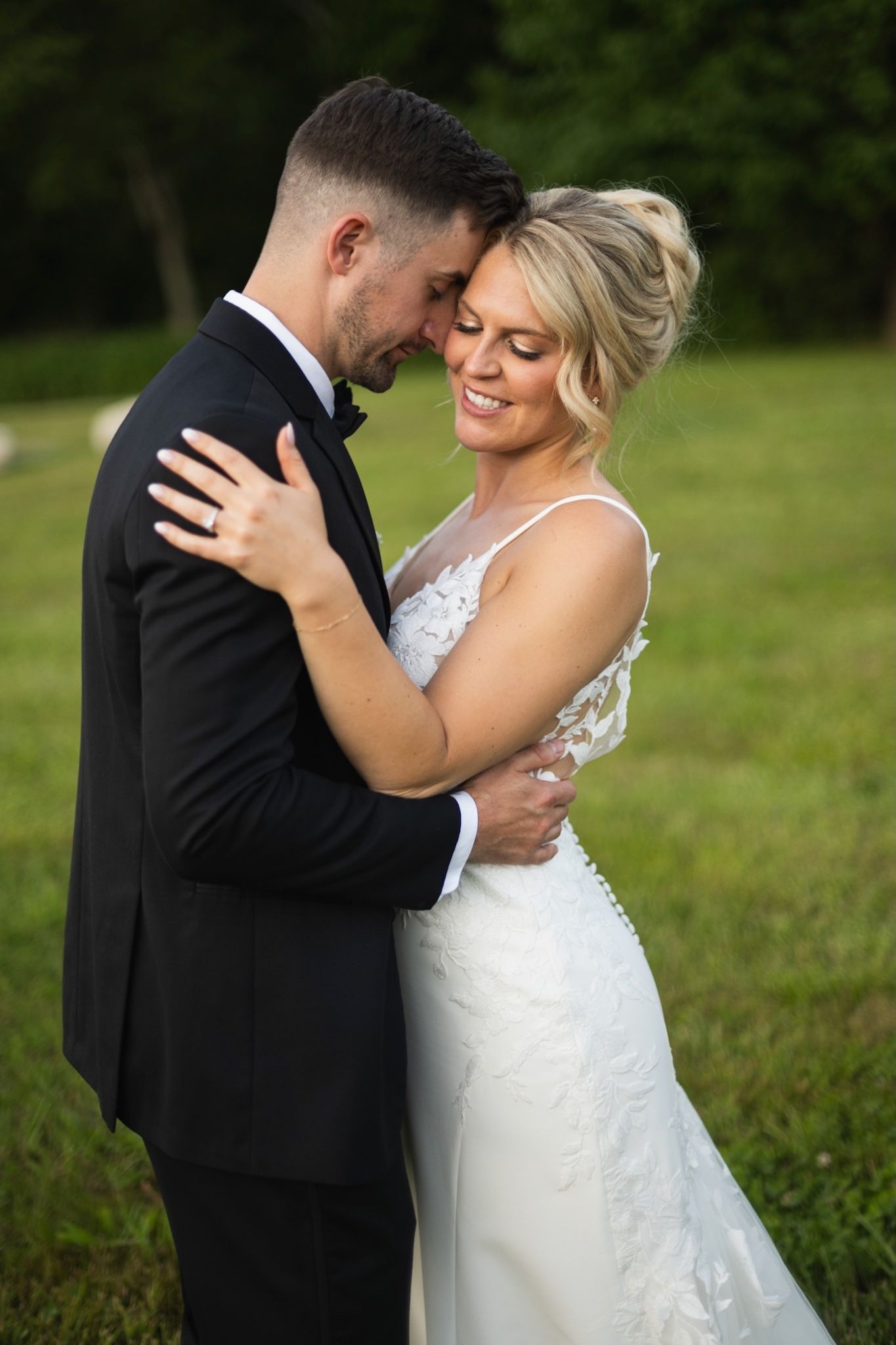 Intimate outdoor wedding portrait with couple embracing in formal attire.