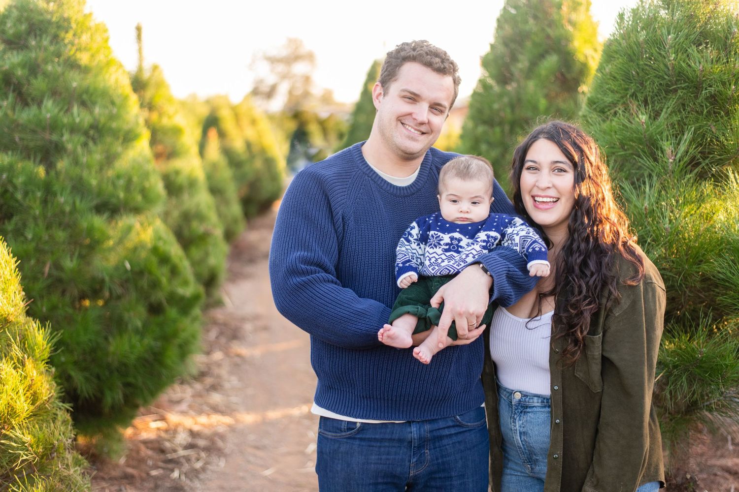 Family posing together at Christmas tree farm during sunset golden hour.