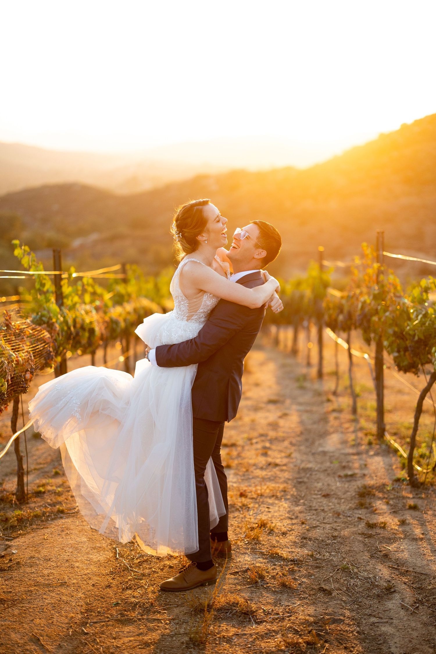 Romantic sunset photoshoot in a vineyard with a couple in wedding attire.