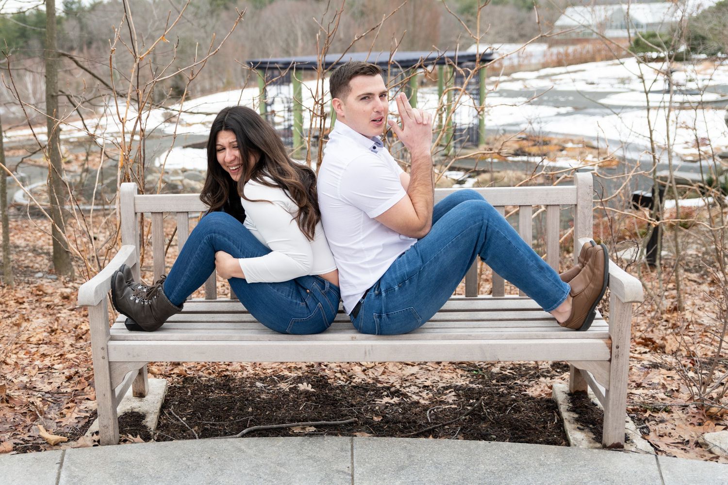 Couple relaxing on wooden bench in casual outdoor setting.