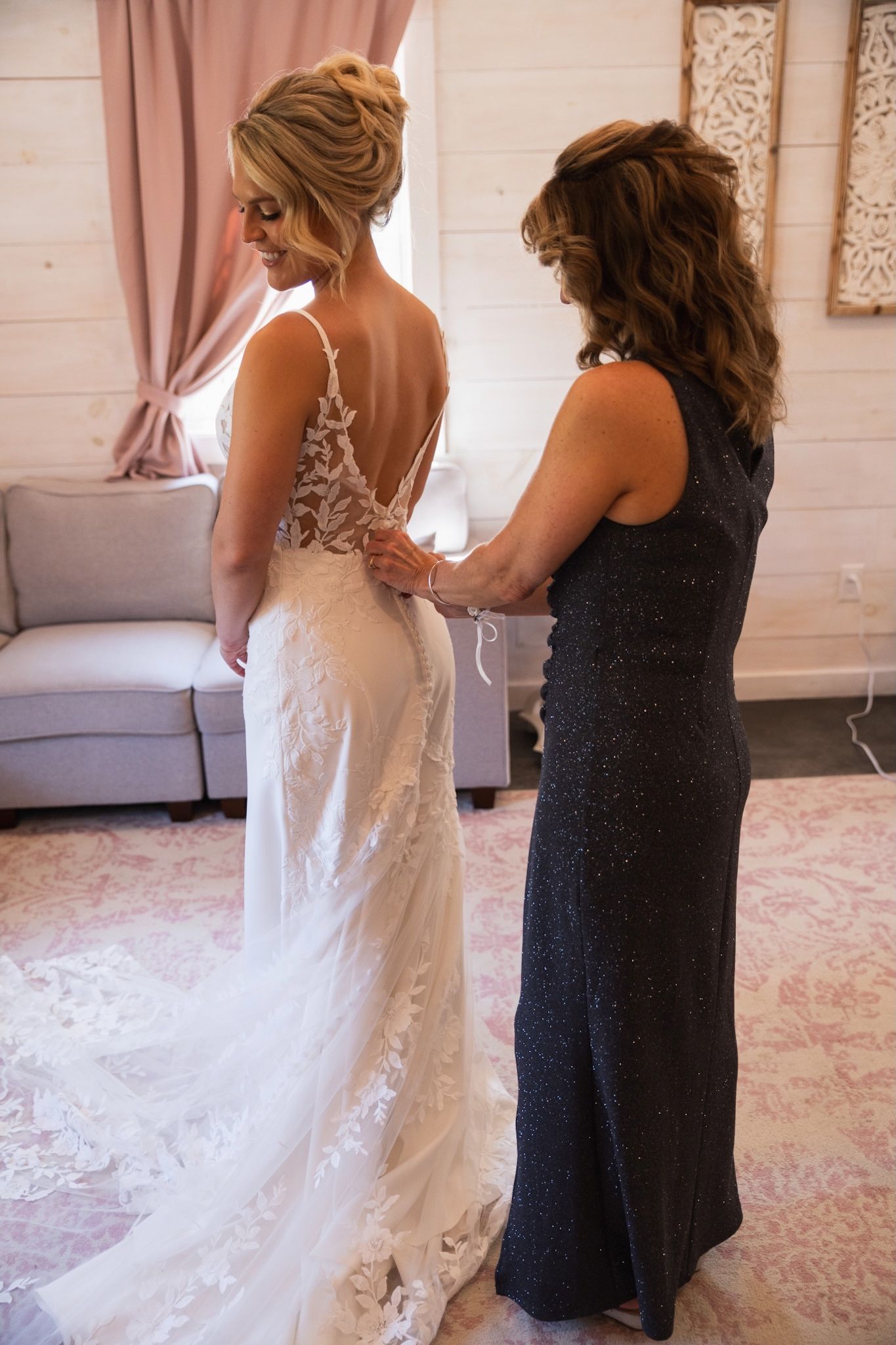 Wedding dress fitting with delicate lace details and navy bridesmaid dress.