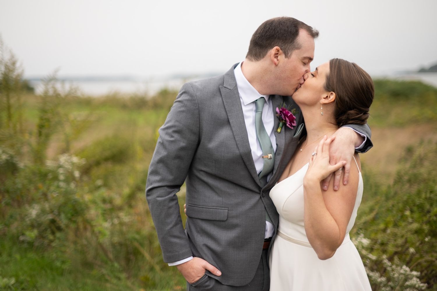 Outdoor wedding portraits of couple sharing romantic moments in a natural field setting.
