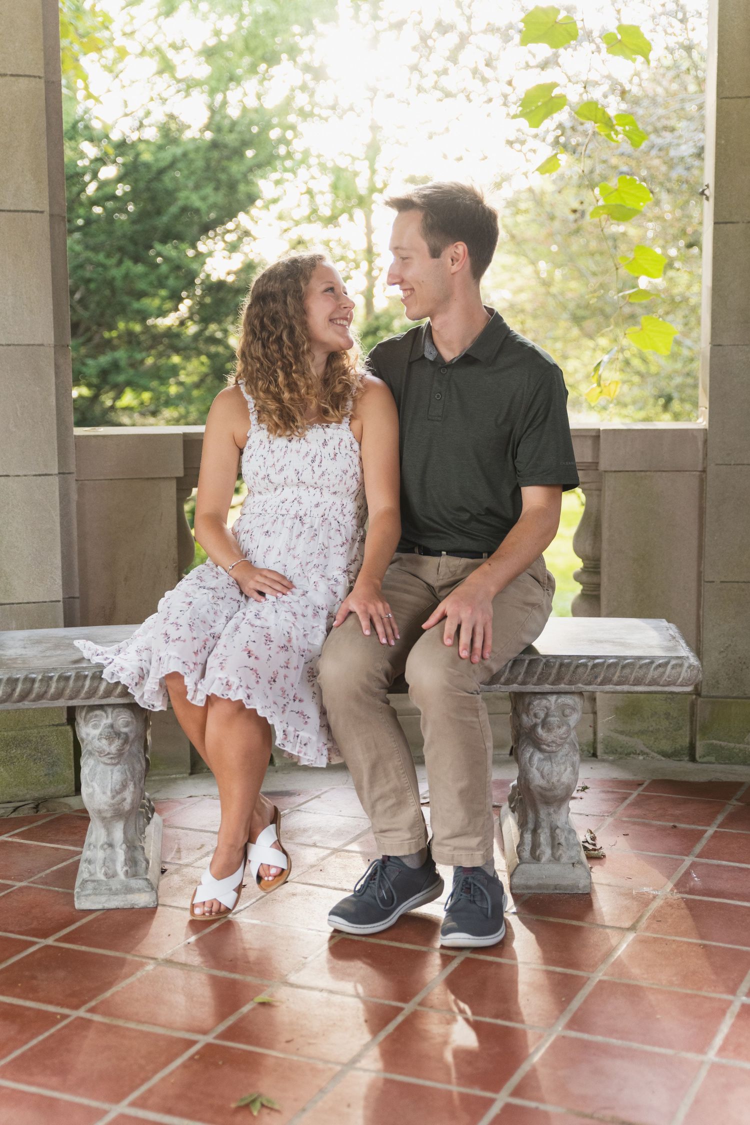 Couple enjoying a sweet moment together while sitting on a porch bench with decorative stone elements.