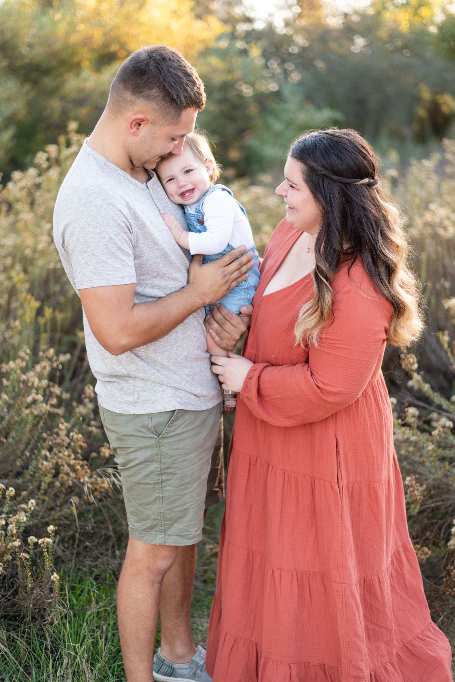 A tender family moment captured at golden hour in a natural outdoor setting.