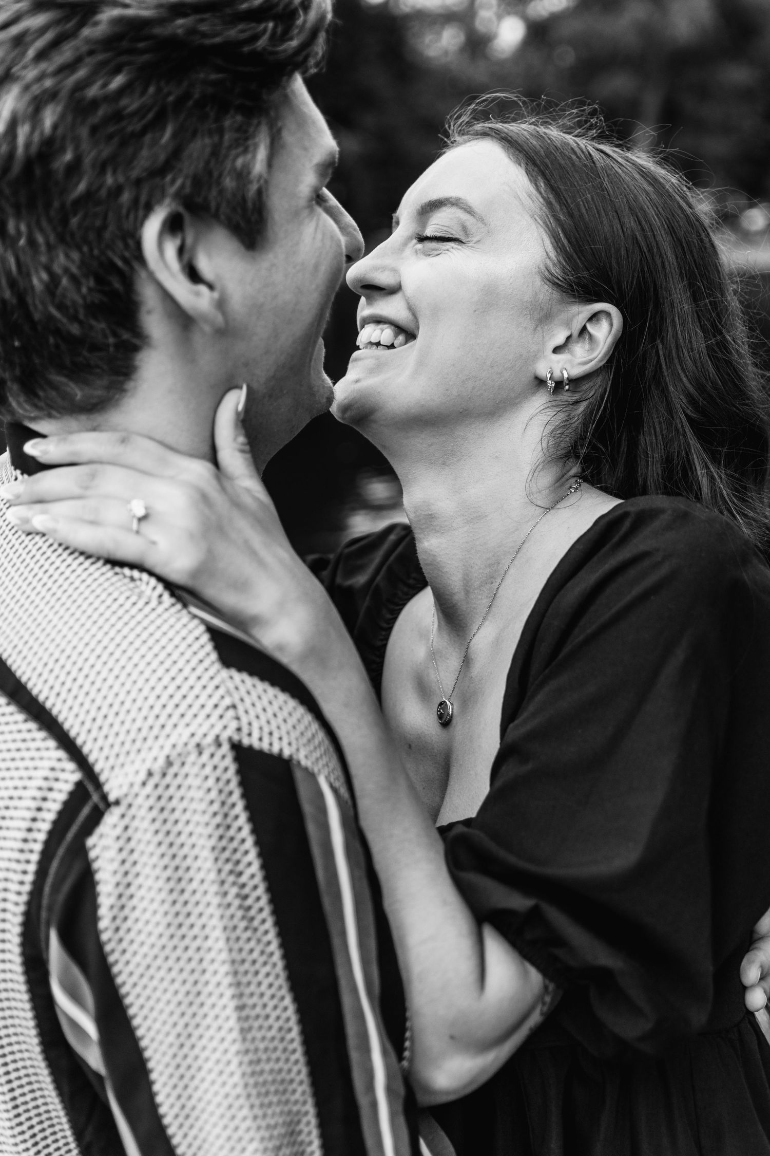 A black and white photo captures two people sharing a joyful laughing moment together.