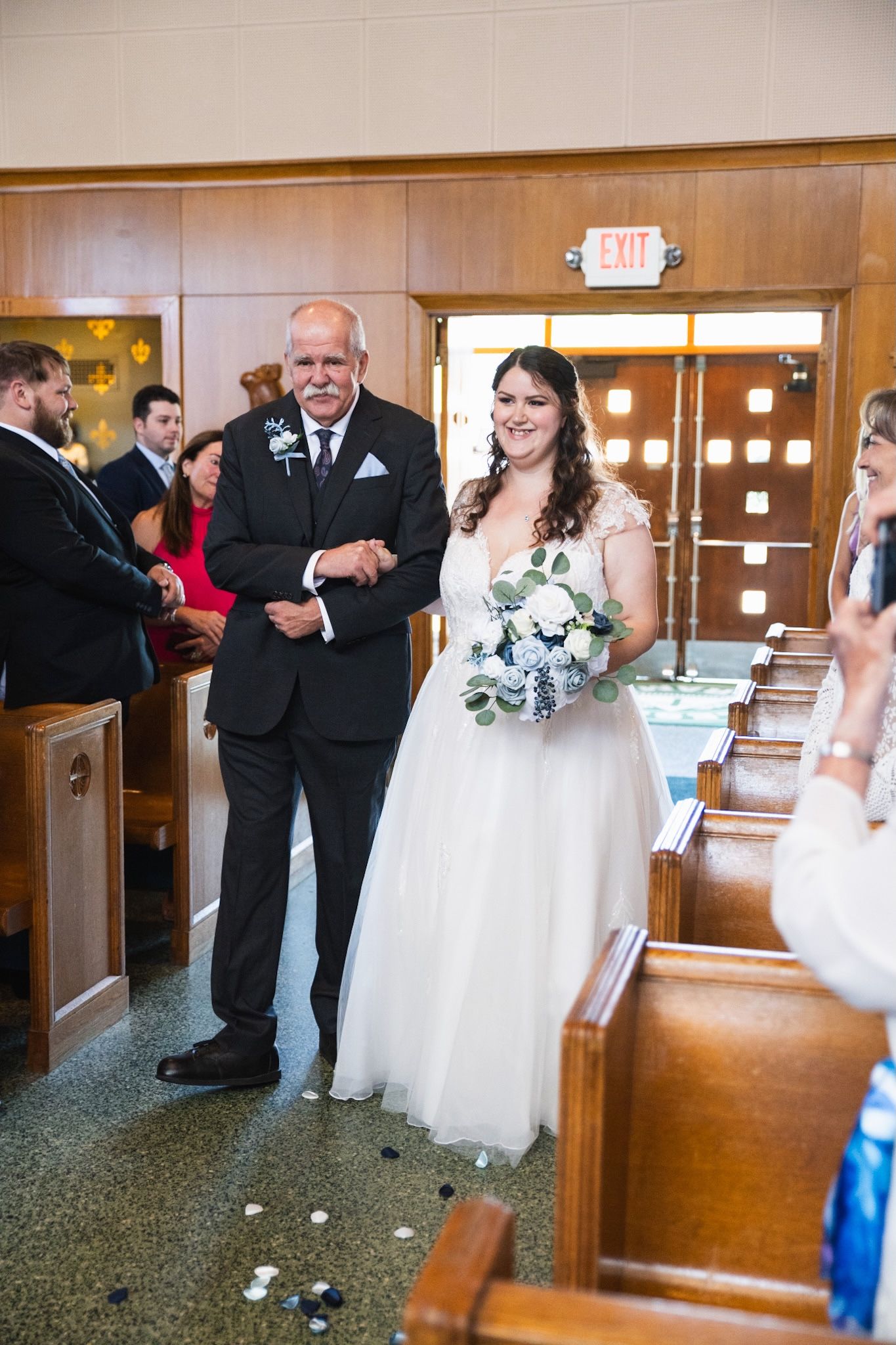 Wedding ceremony in traditional church setting with wooden pews and floral decorations.