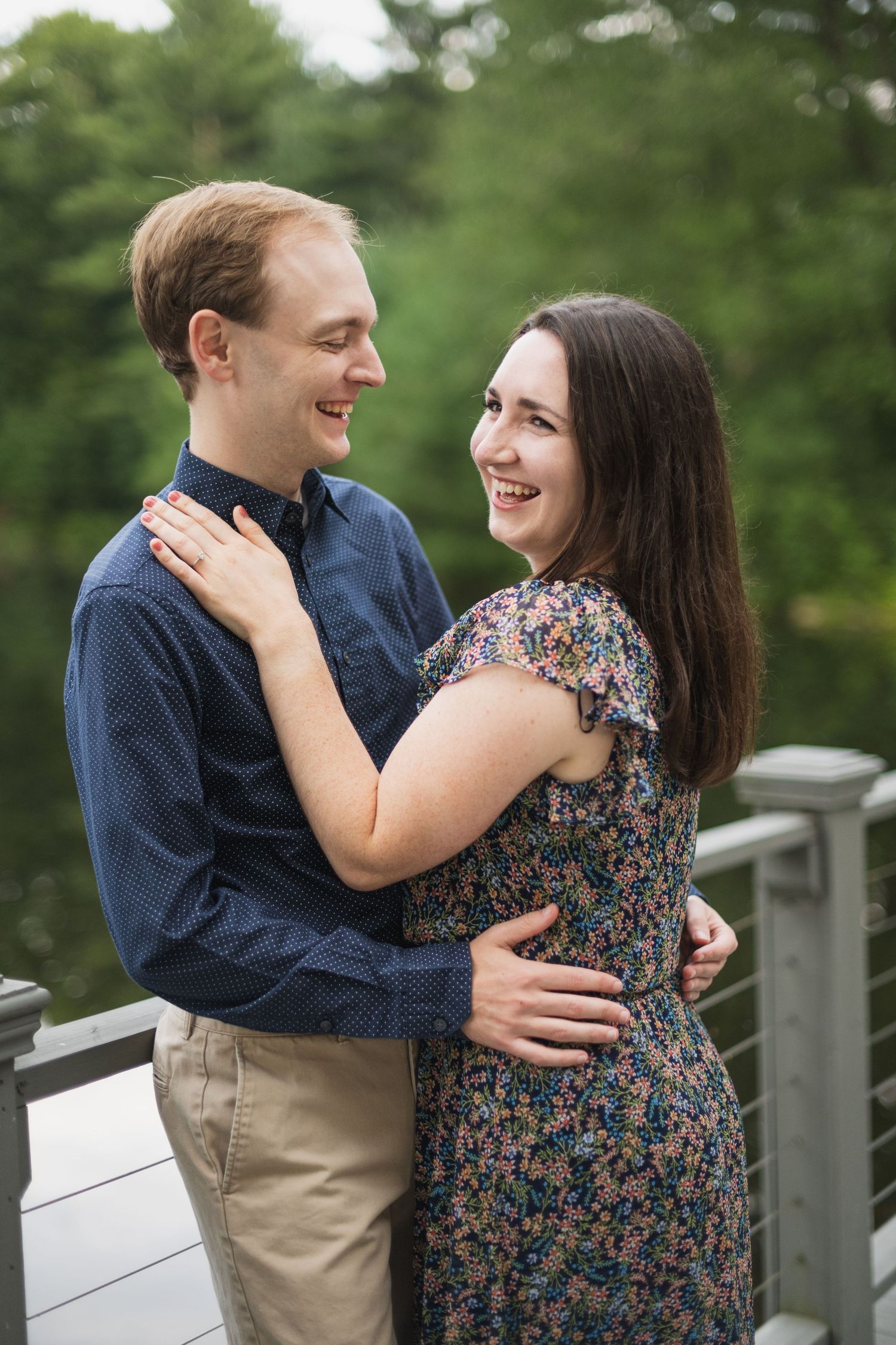 A joyful couple laughs together while embracing on an outdoor deck.