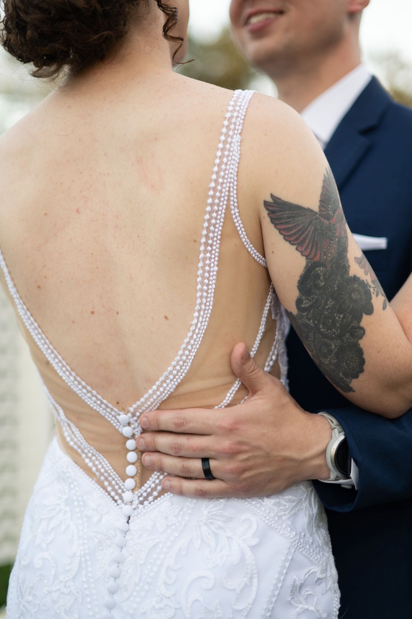 Close-up of an elegant beaded wedding dress back with visible tattoo art.