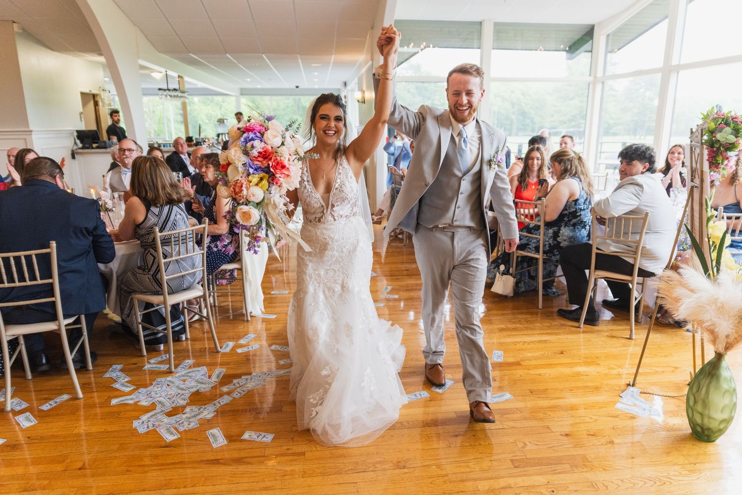 Wedding reception venue with large windows and natural light streaming onto wooden dance floor.