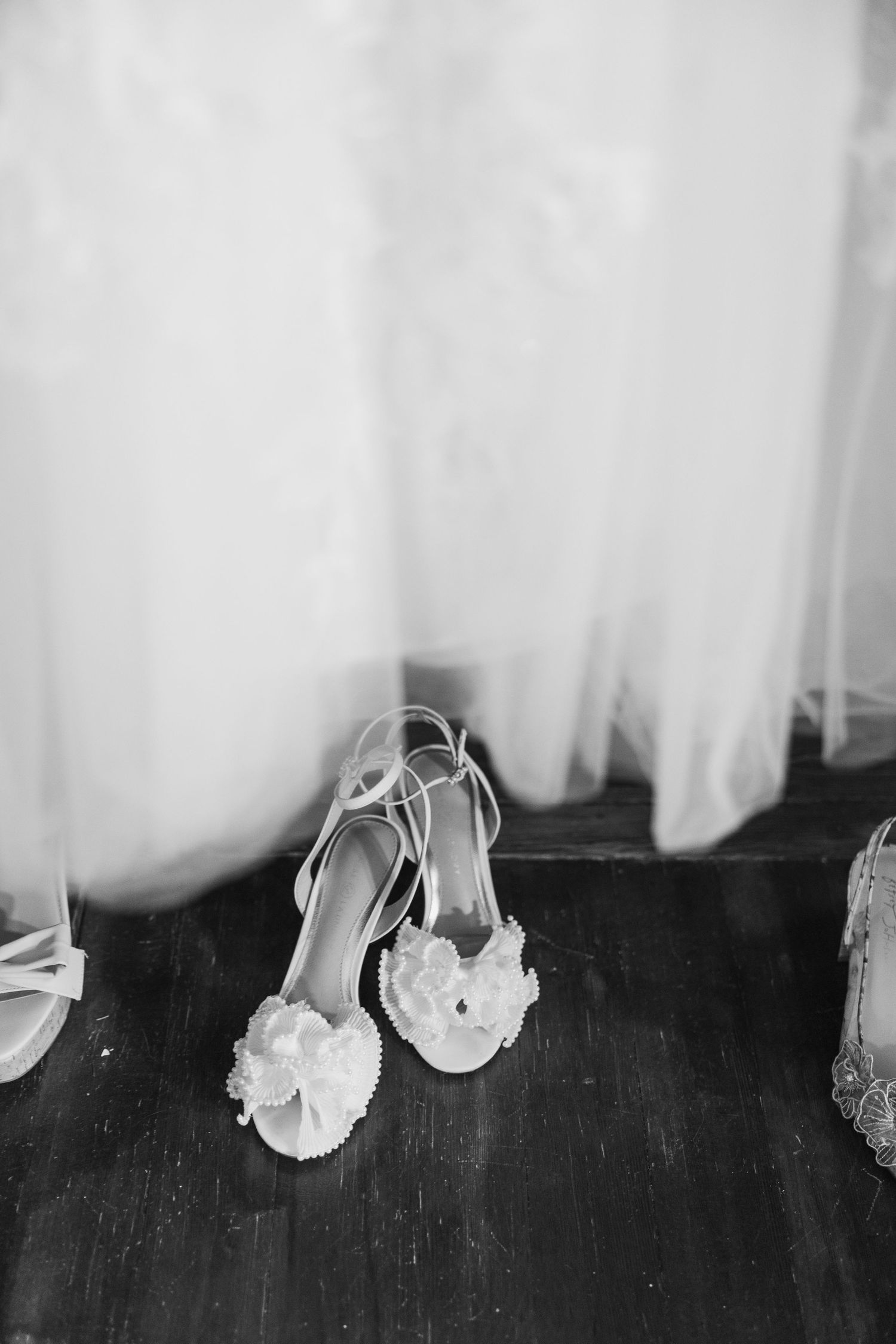 Collection of elegant bridal shoes arranged in black and white photography.