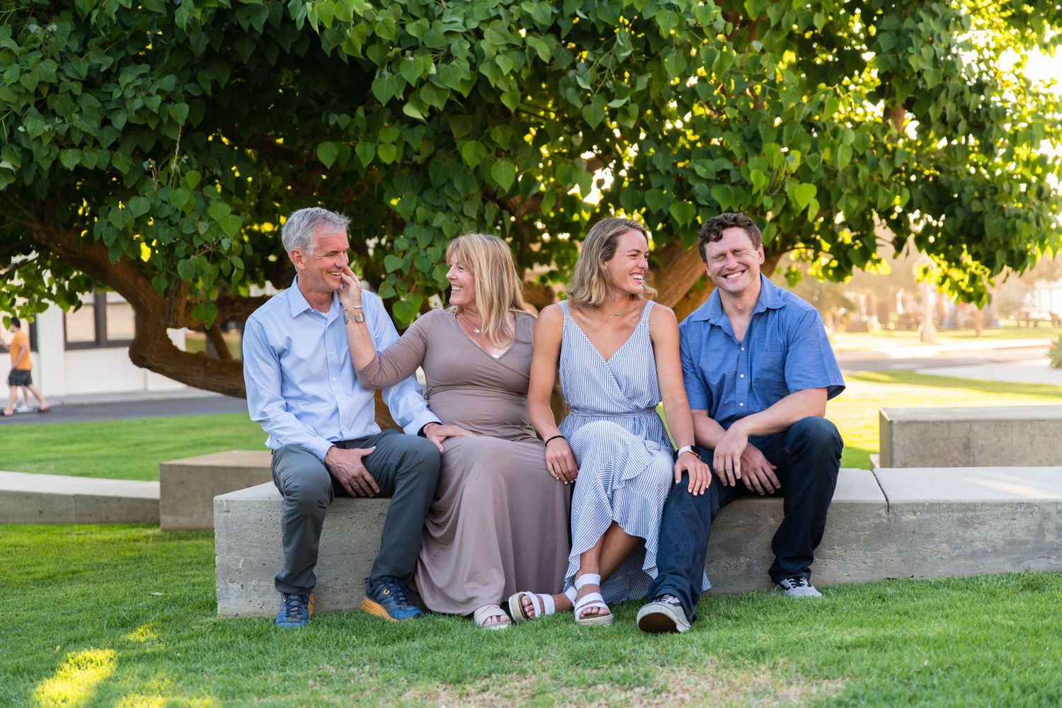 Family relaxing together on grass during golden hour outdoor photo session.
