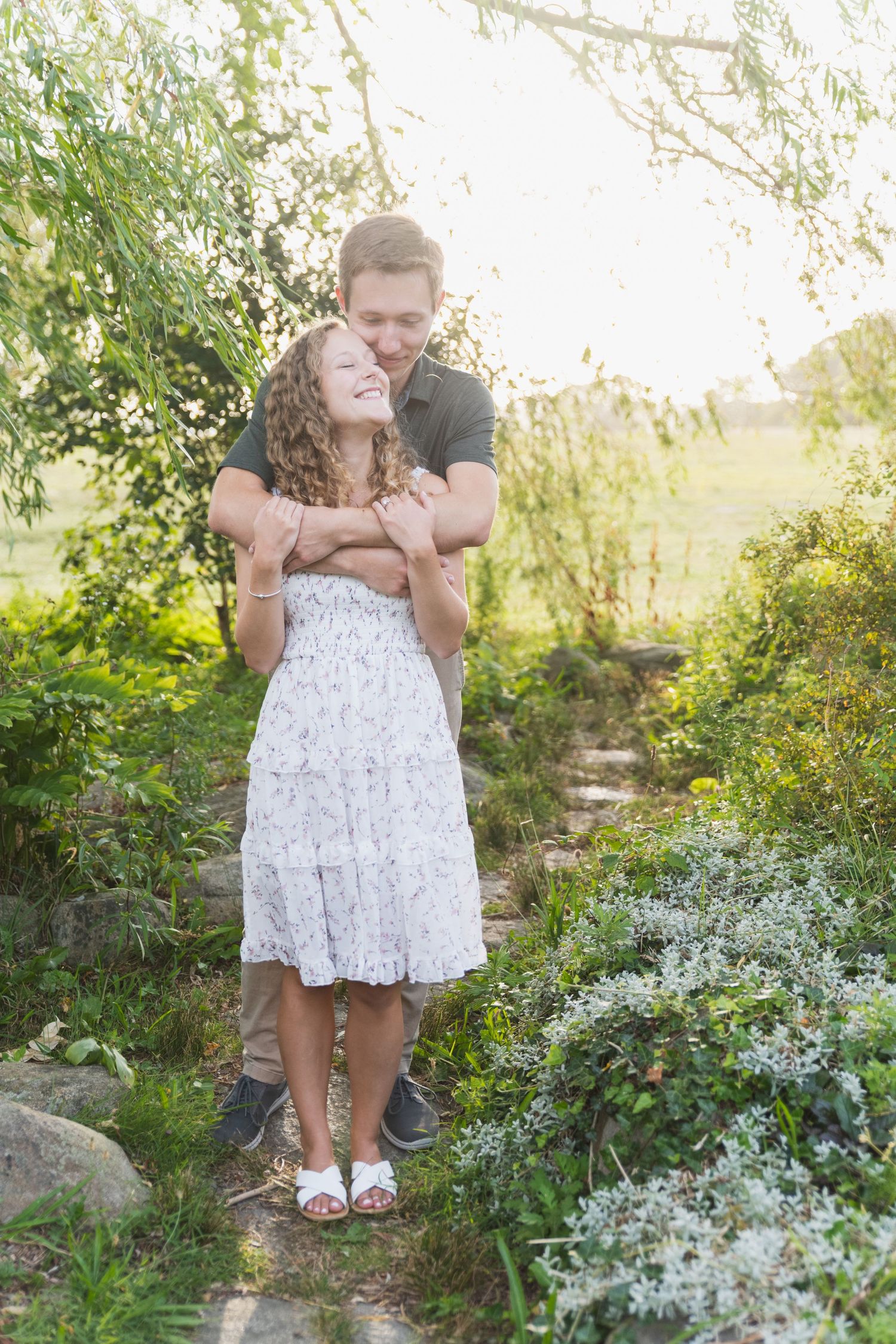 Romantic couple sharing tender moments in a garden setting surrounded by white flowers and greenery.