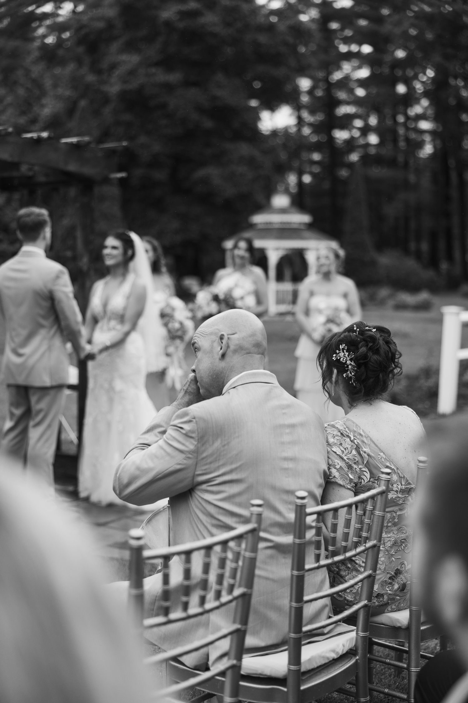 Wedding ceremony guests seated in rows of elegant chairs outdoors.