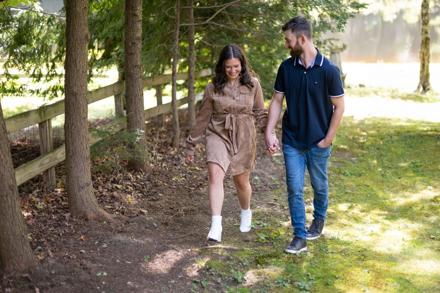 A couple walks playfully along a wooded trail during a summer afternoon.