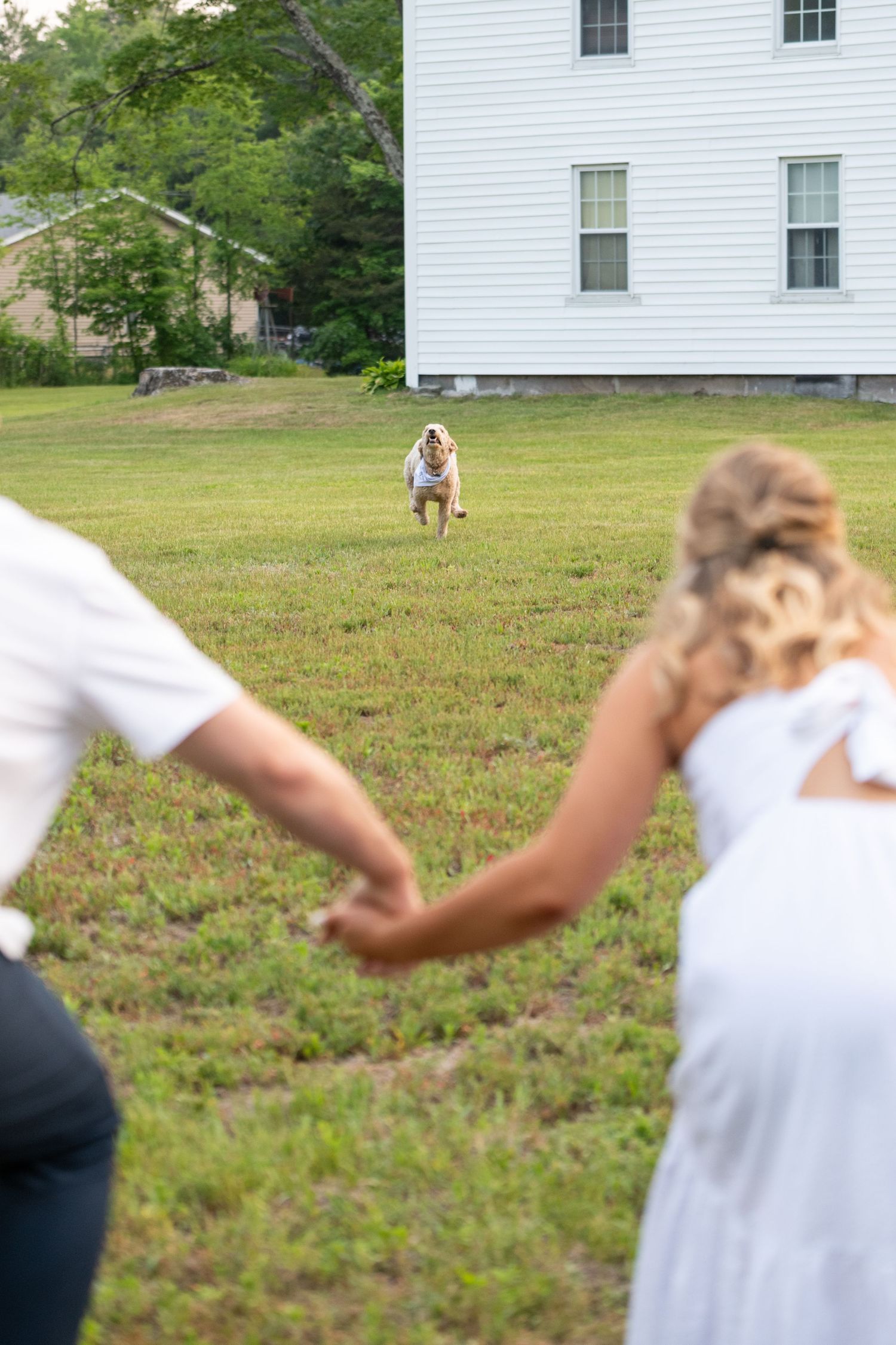 Couple dancing playfully in front of white colonial style building.