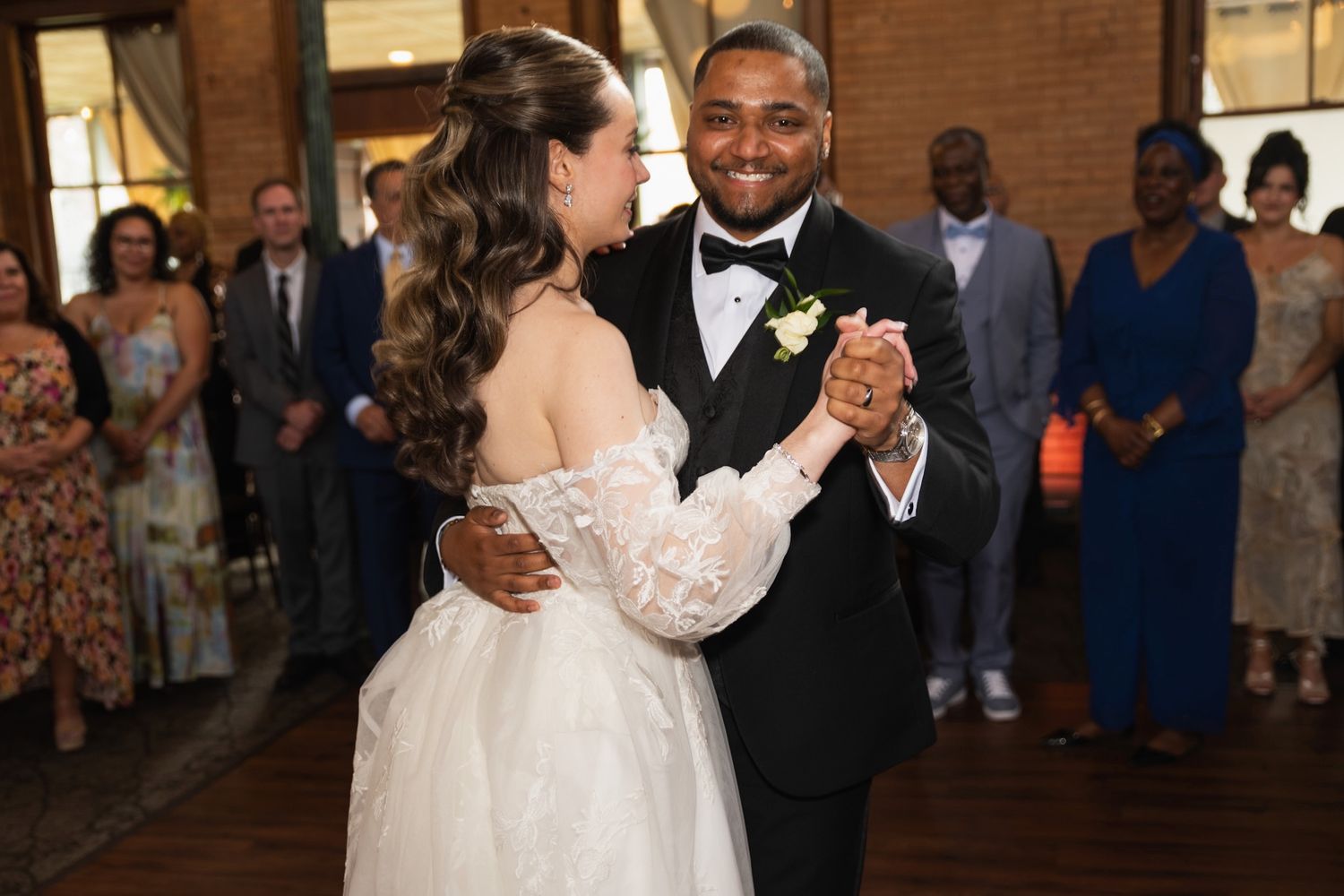 Wedding couple sharing their first dance with guests watching in background.