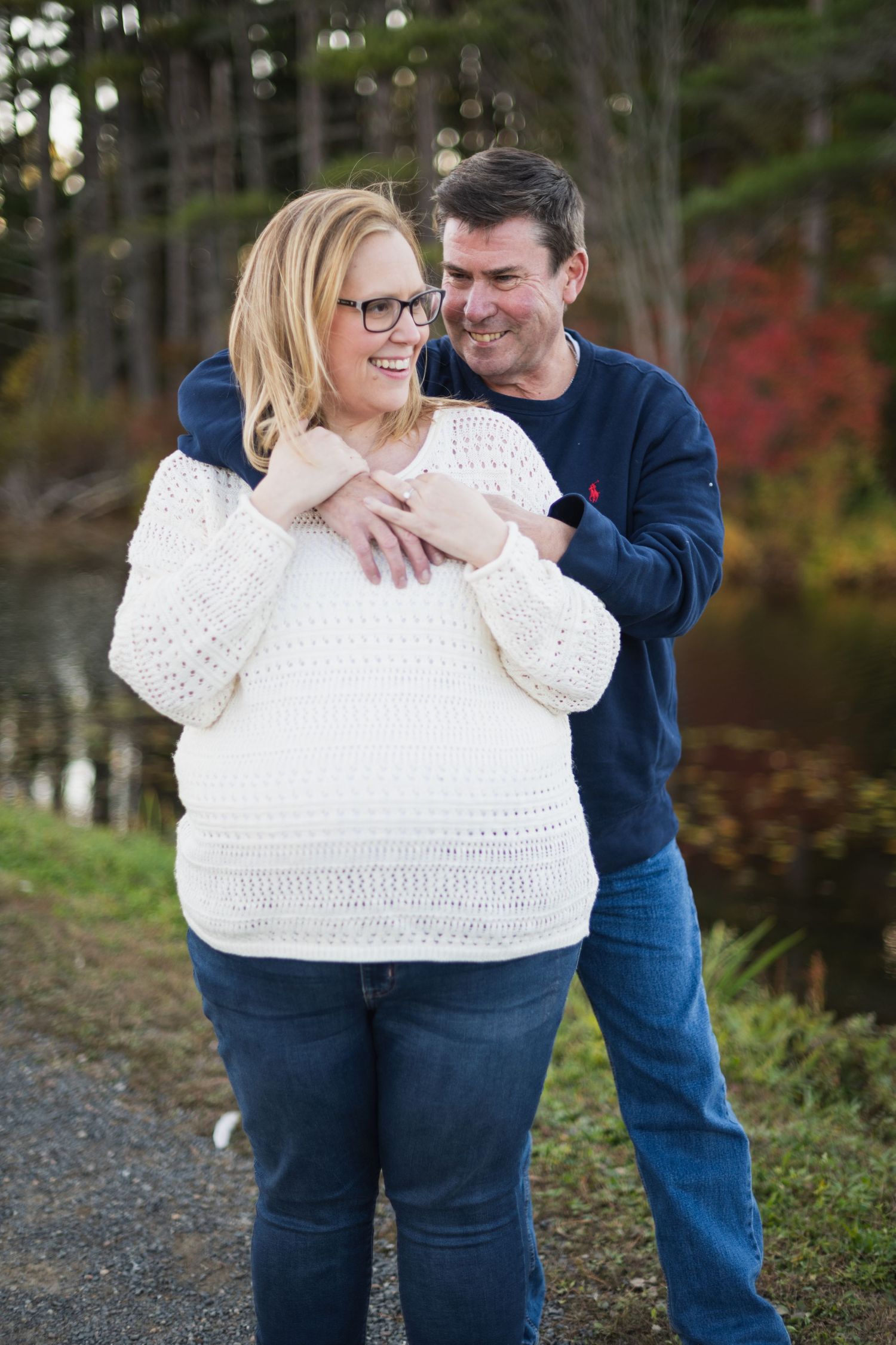 Couple in casual attire sharing a tender moment outdoors against autumn foliage.