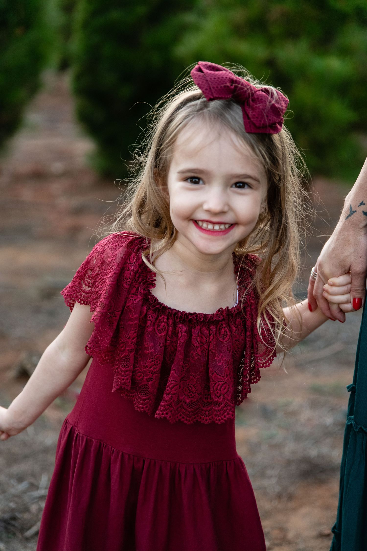 Young child in a burgundy dress with lace details twirling and smiling.