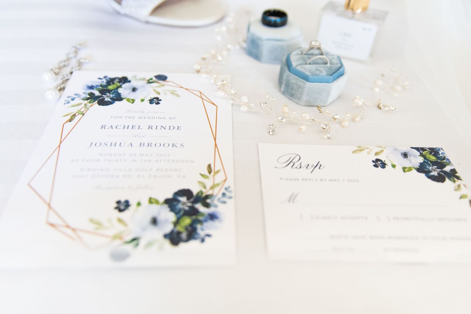 Wedding stationery flat lay featuring delicate blue floral designs and elegant calligraphy.