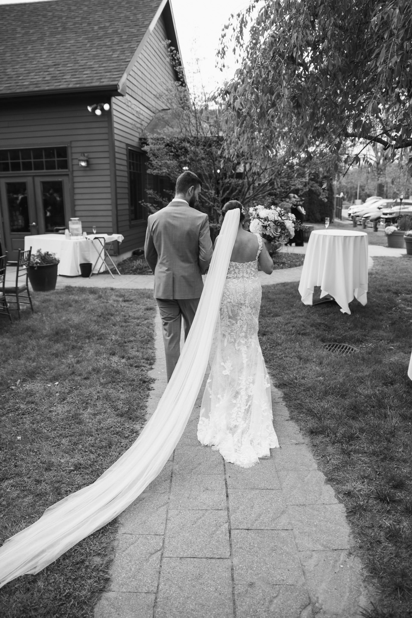 Wedding dress with flowing train displayed along stone pathway leading to venue.