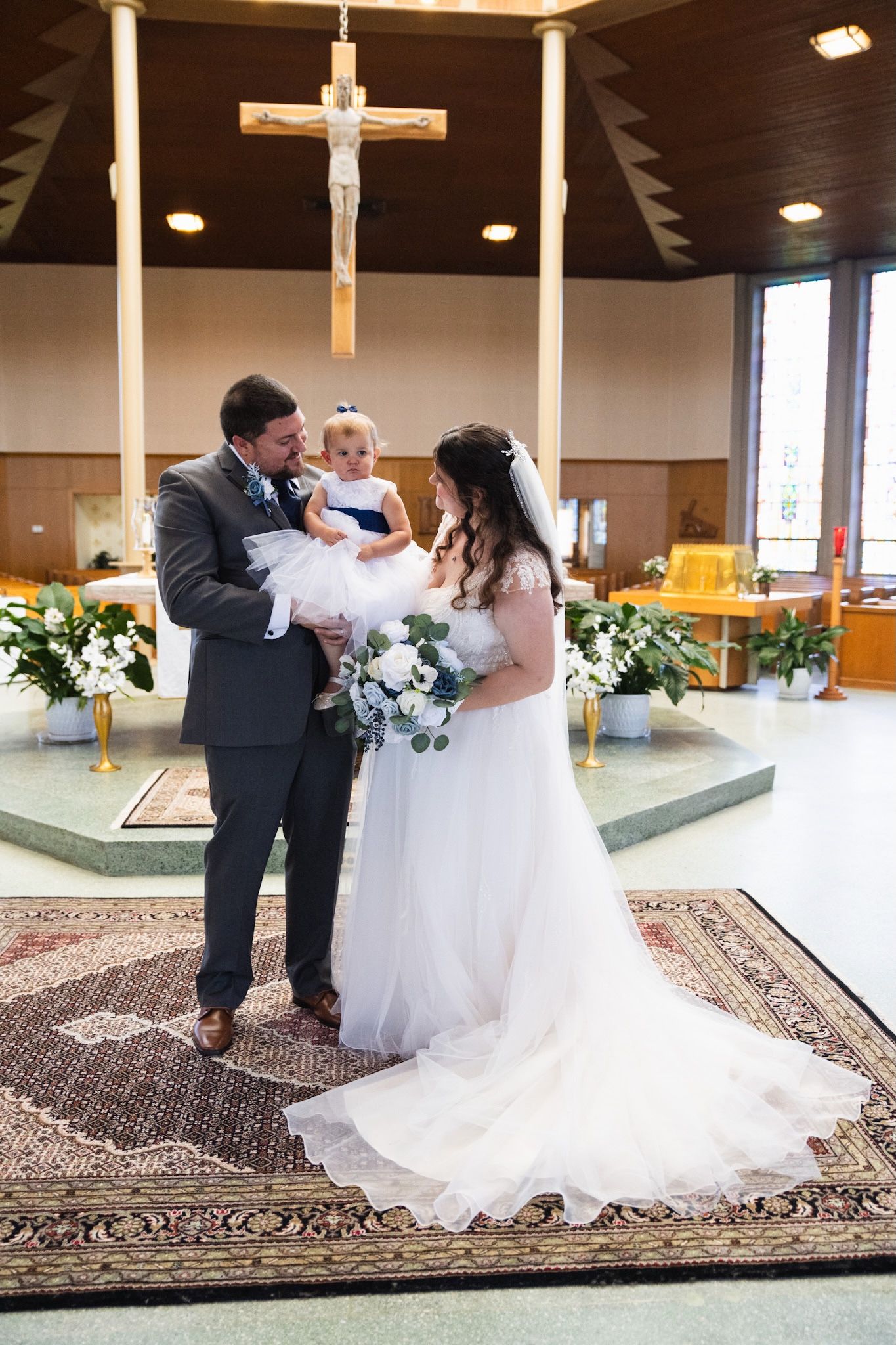Wedding ceremony moments captured inside church with wooden cross and decorative carpet.