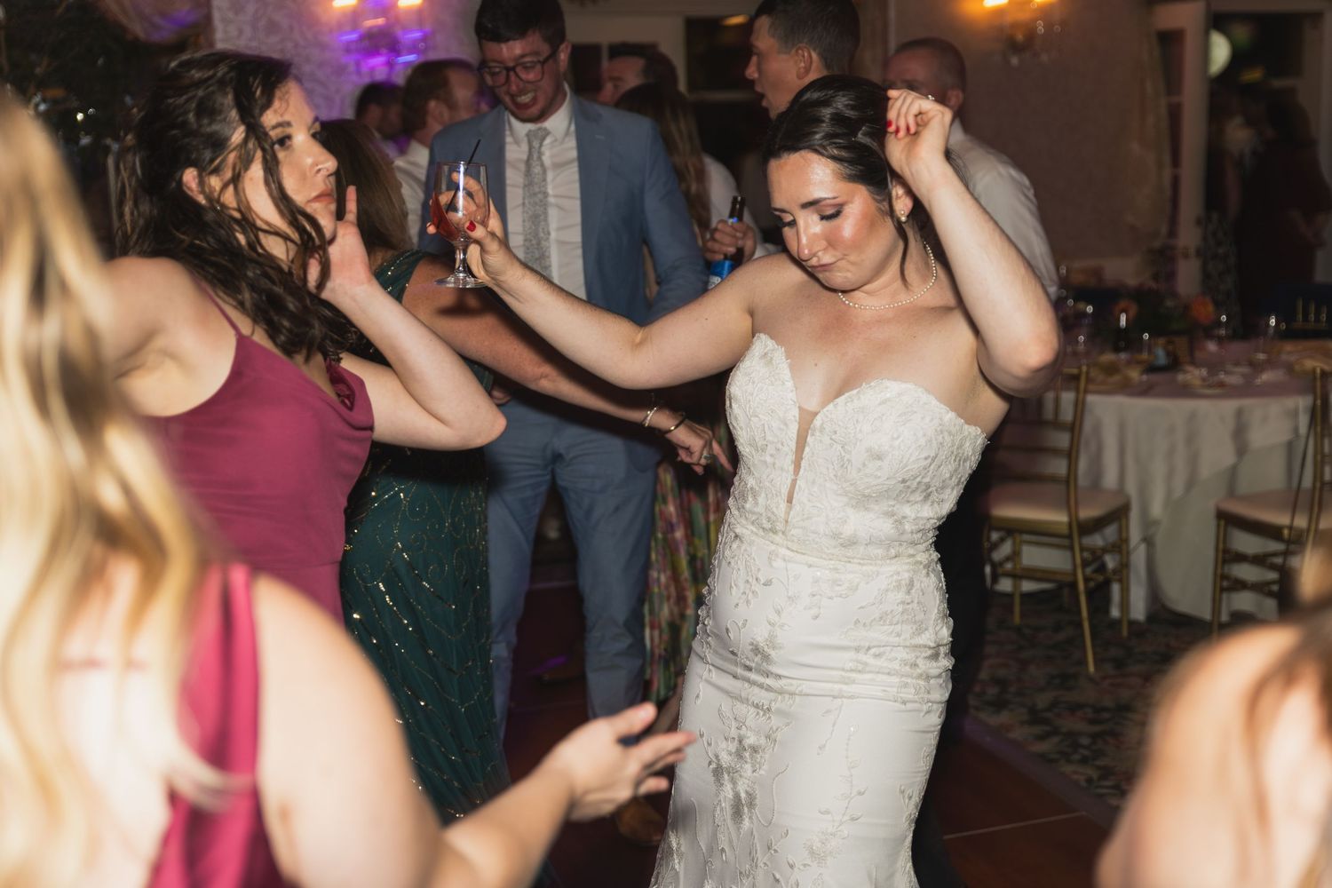 People dancing and celebrating at a wedding reception with colorful lights and festive atmosphere.