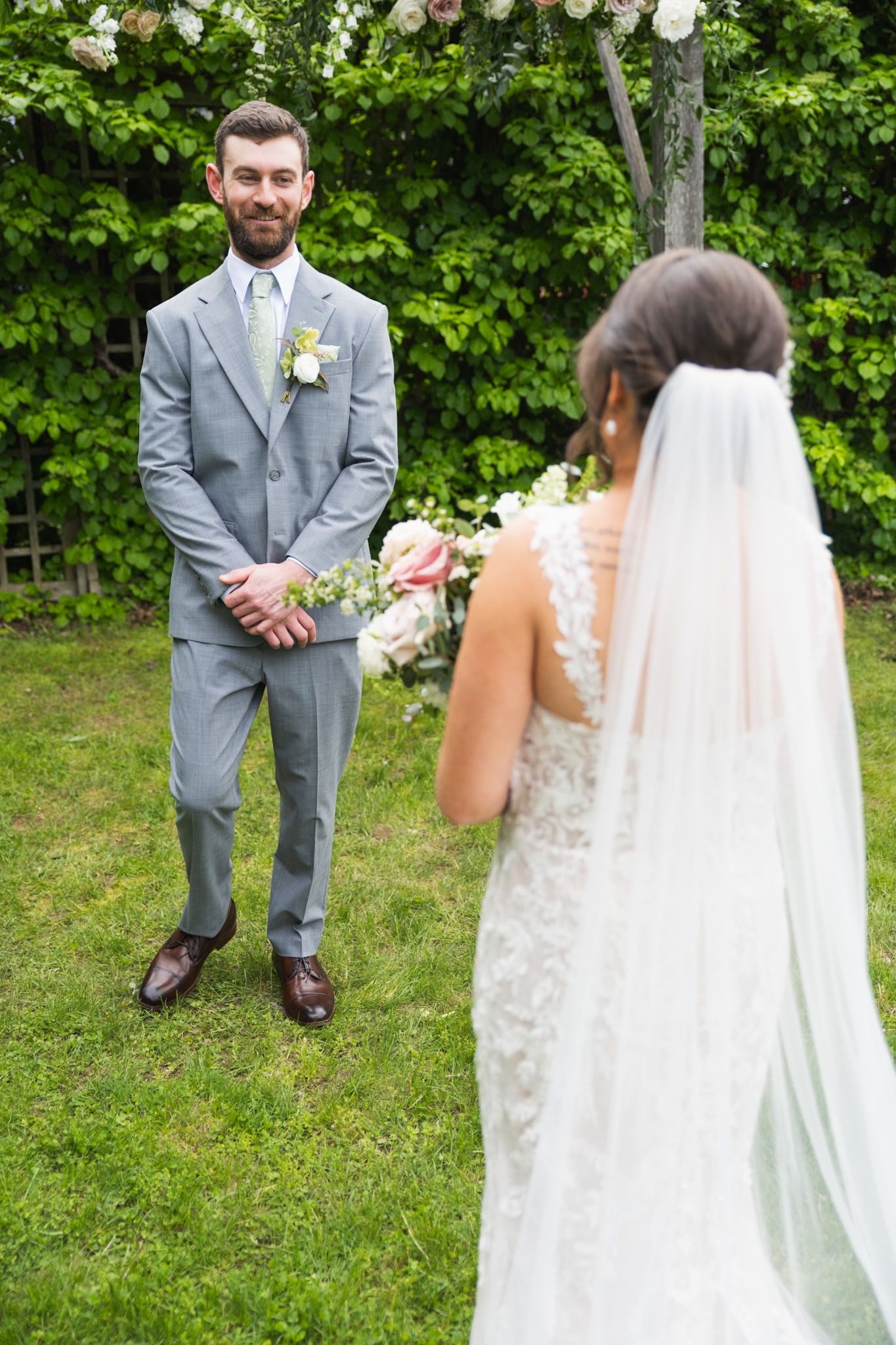 First look wedding moment captured in sequence on a grassy lawn with white floral arrangements.