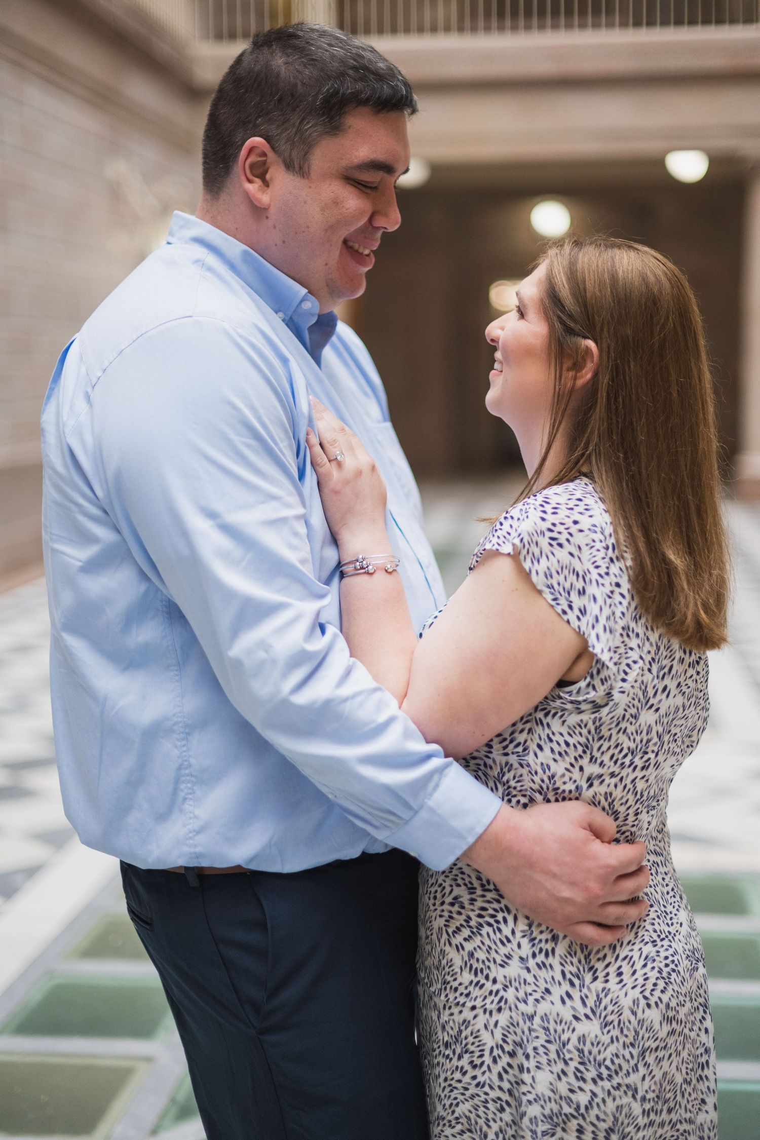 Romantic engagement photo series showing a couple embracing in matching business casual attire.