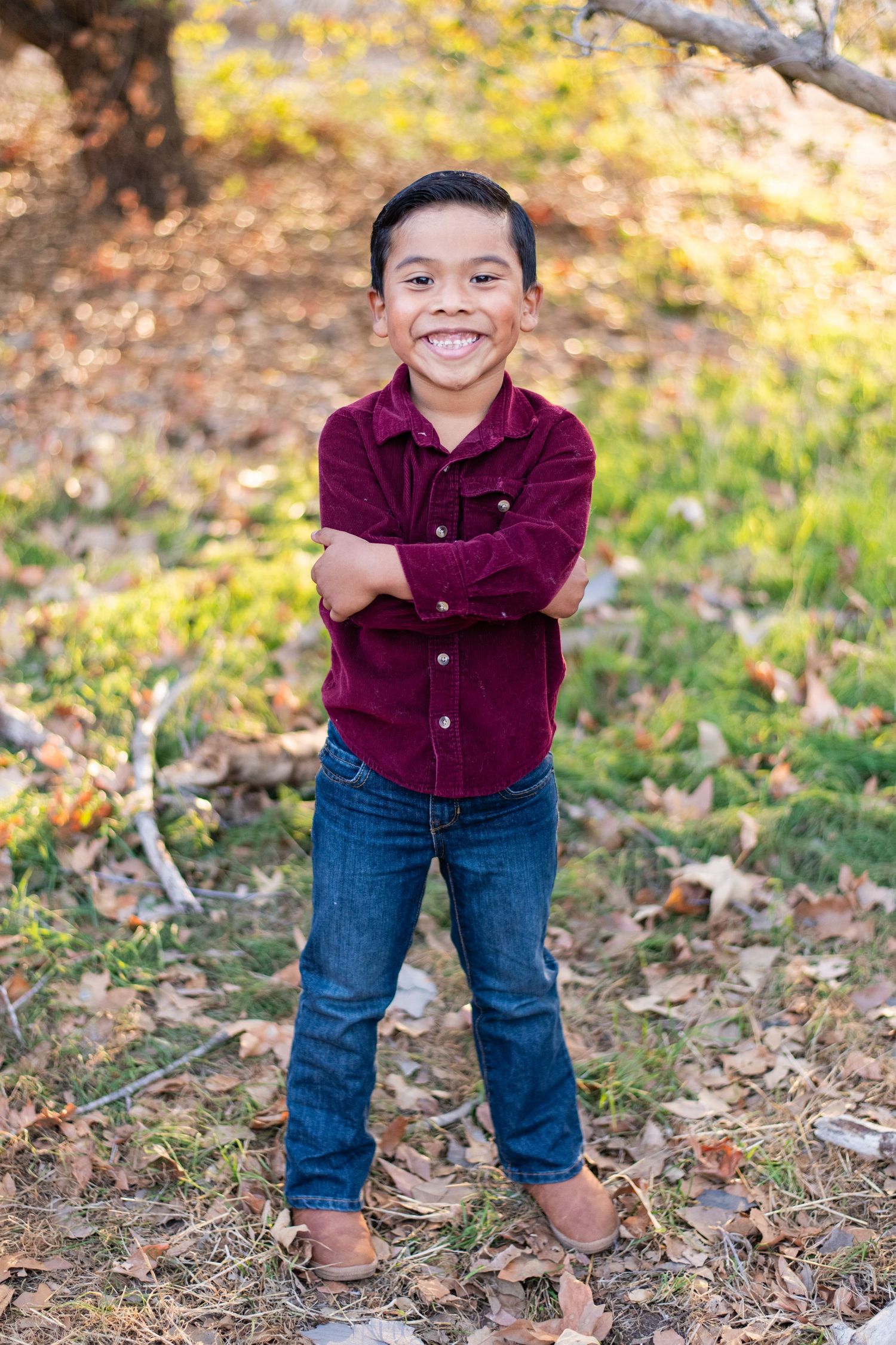 Fall outdoor portrait session in burgundy shirt and jeans among autumn leaves.