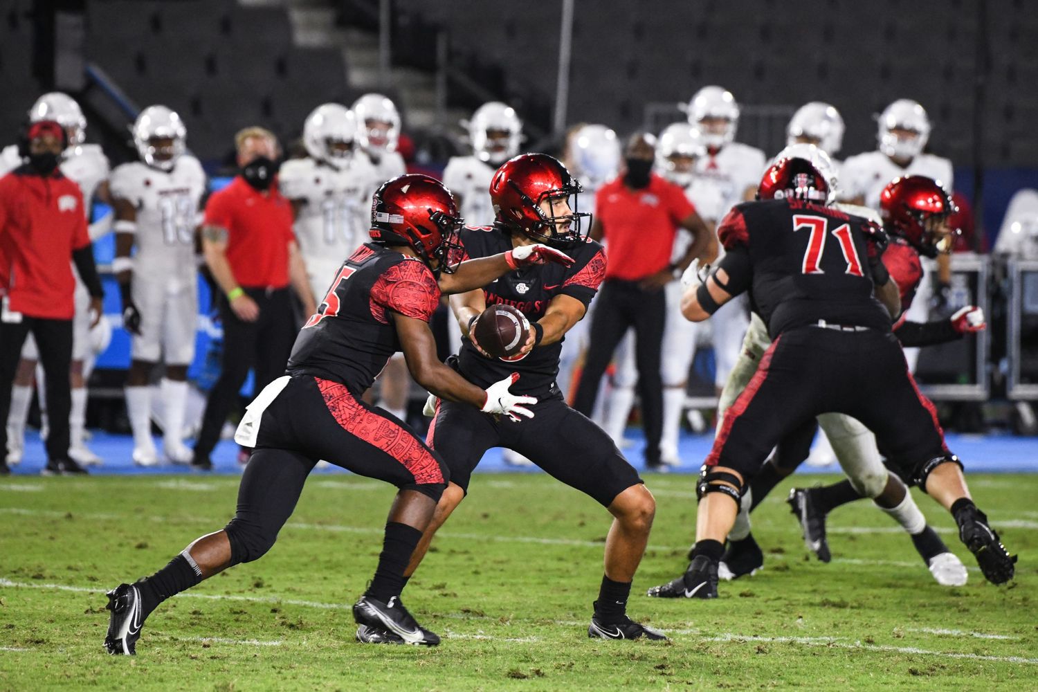San Diego State football players execute a handoff play during a night game at the stadium.