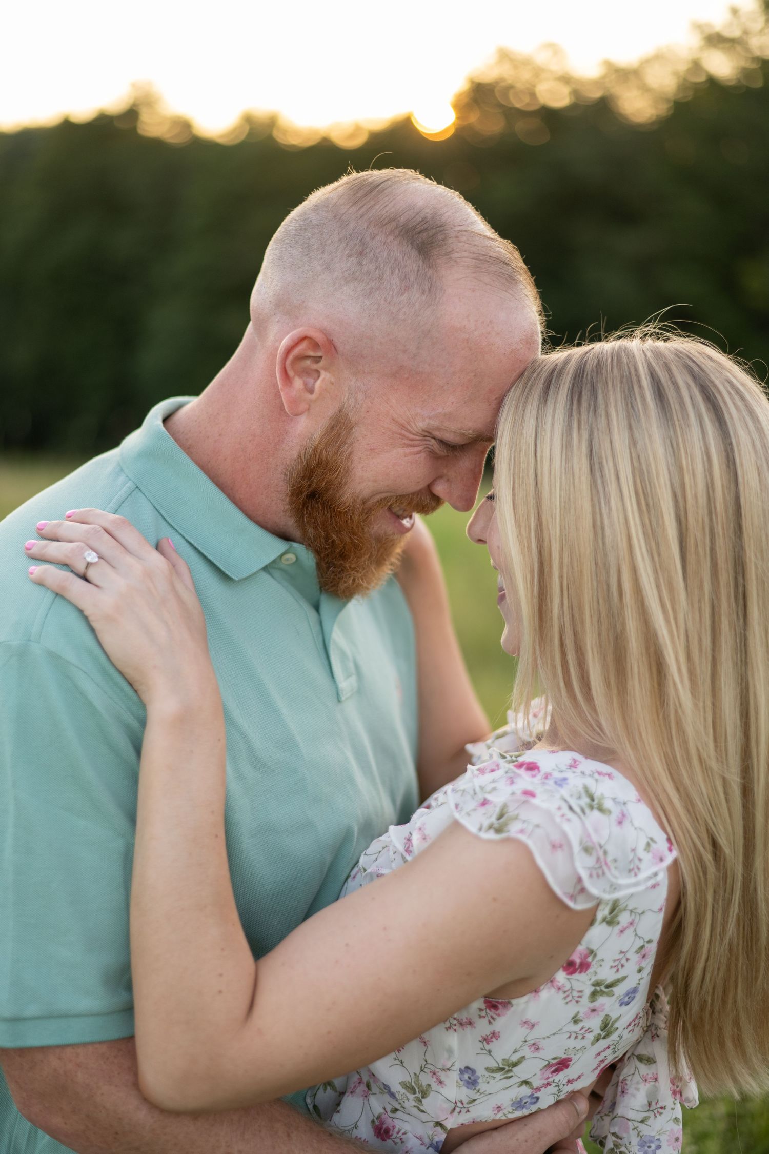 Couple embraces tenderly during sunset photoshoot in mint green and floral attire.